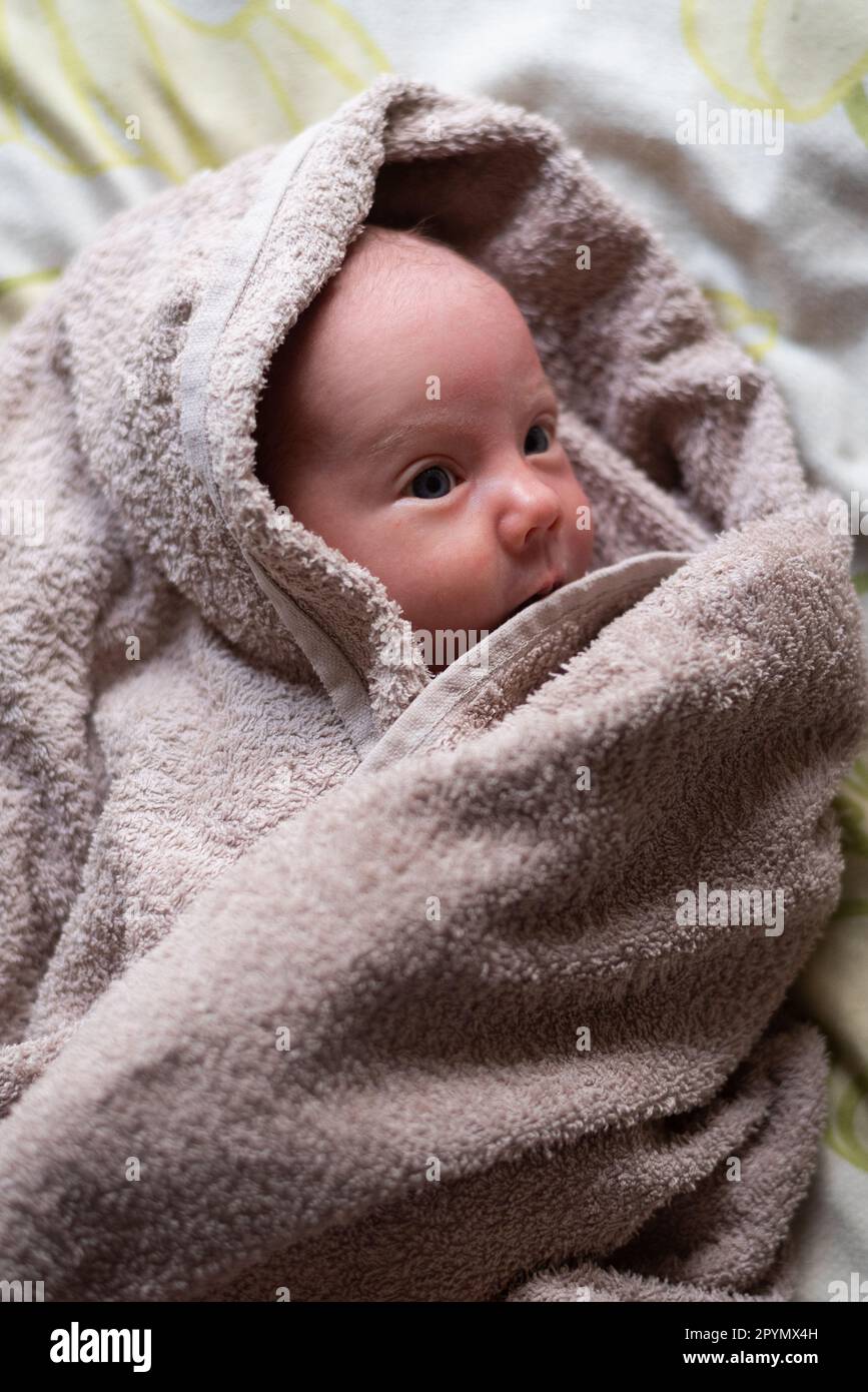 A peaceful and calm baby wrapped up in a towel after bath time to dry