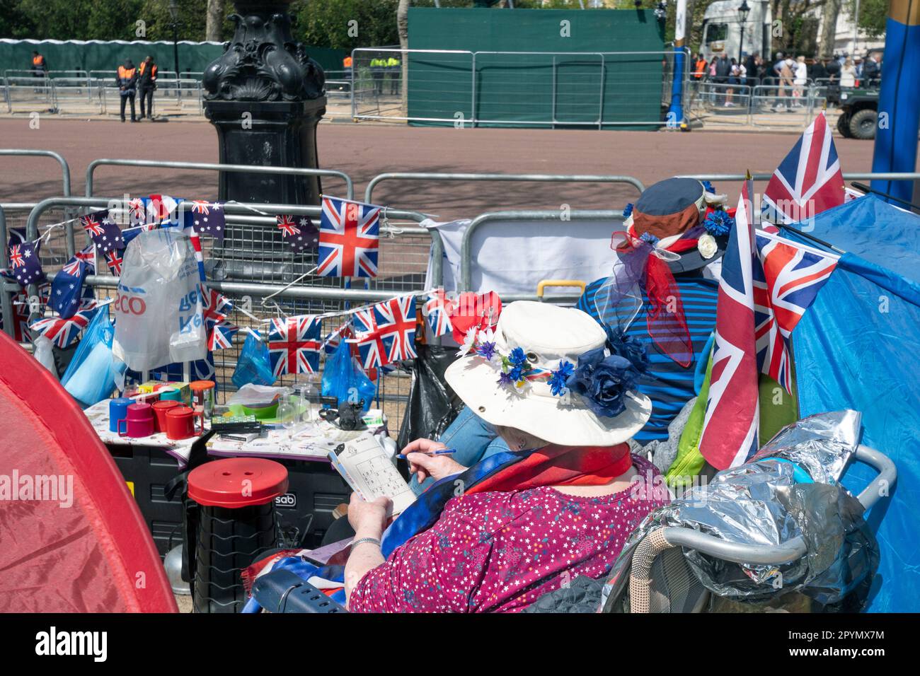 London UK May 3 2023 THE MALL  Avid royalist fans camping at  their positions at the guard rails along the Mall ahead of the coronation of King Charles III and Queen Ca.milla on 6 May. NOTE Woman doing a crossword puzzle . Credit Gary Blake / Alamy live news Stock Photo
