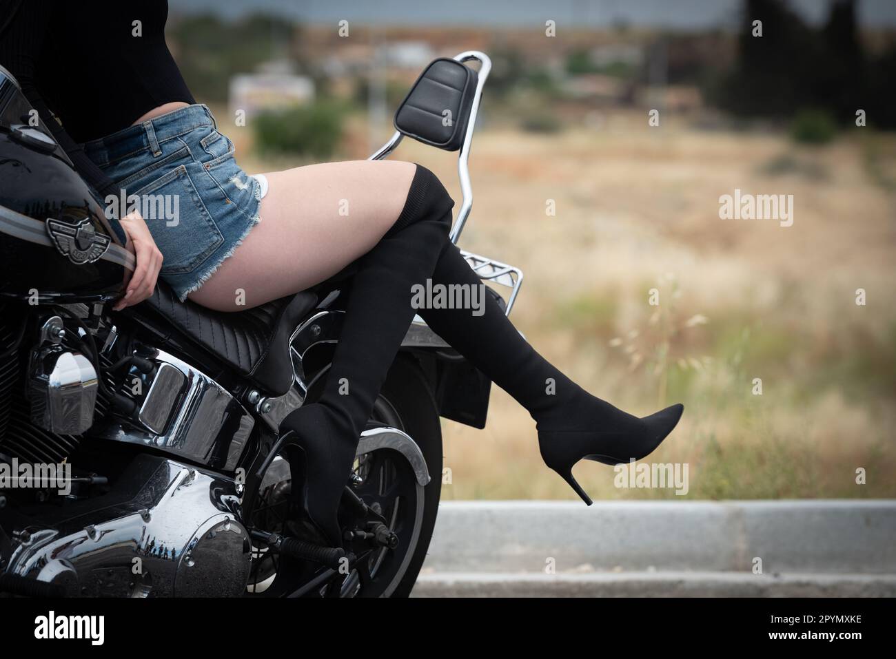 Sexy woman wearing high black heels riding a street motorbike outdoors. Exploration and adventure, street bike. Stock Photo
