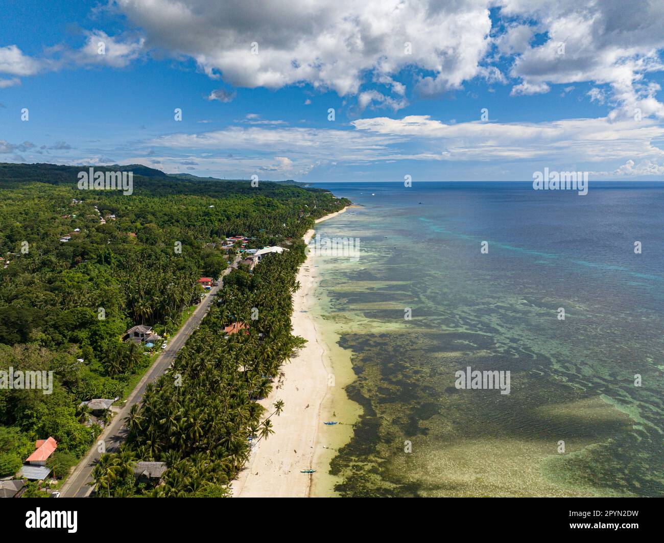 White shiny seashore with turquoise lagoon of coral reefs along with the healthy coconut trees. Siquijor, Philippines. Stock Photo