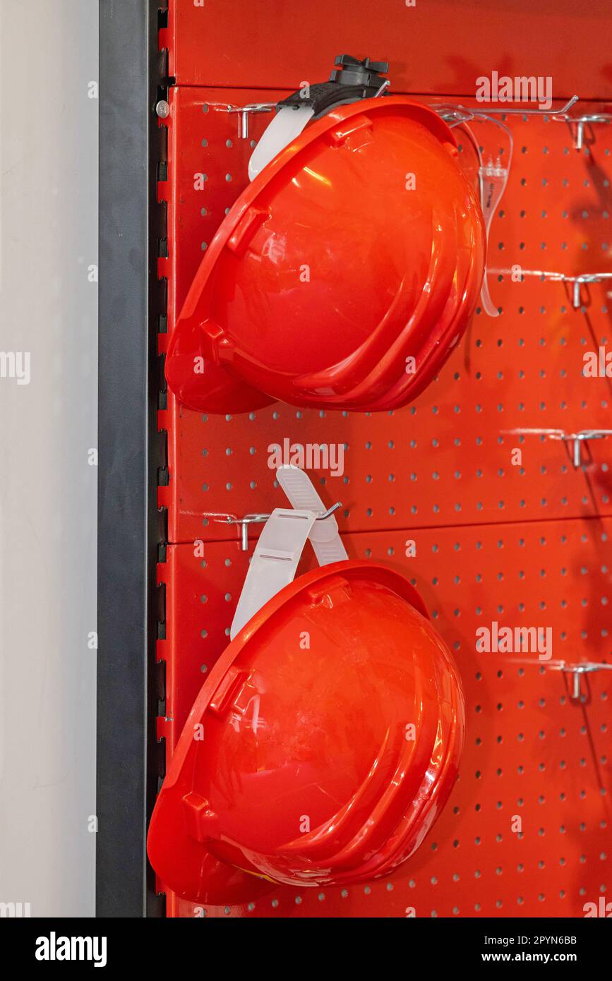 Two Red Plastic Hard Hats at Wall Shelf Rack Personal Protective