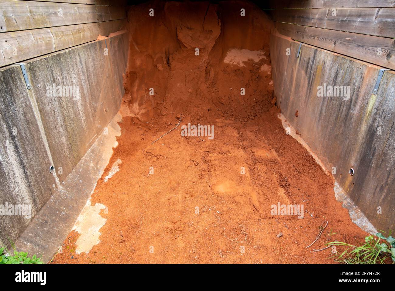 Red gravel for tennis court surface made of crushed brick, stone or shale mixed with sand stored under wooden shelter, Netherlands Stock Photo