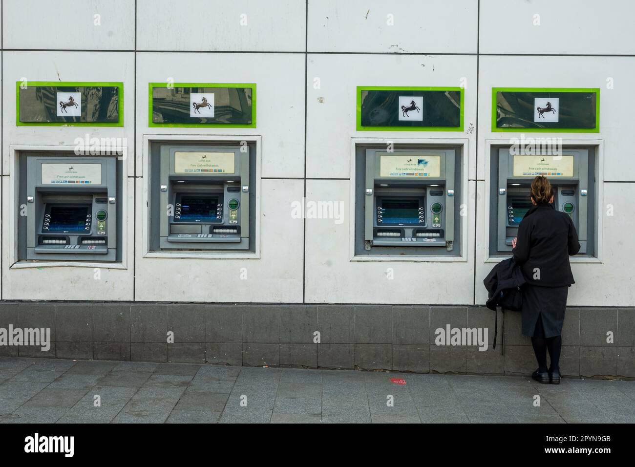 Woman at a row of ATM cash machine terminals. Stock Photo