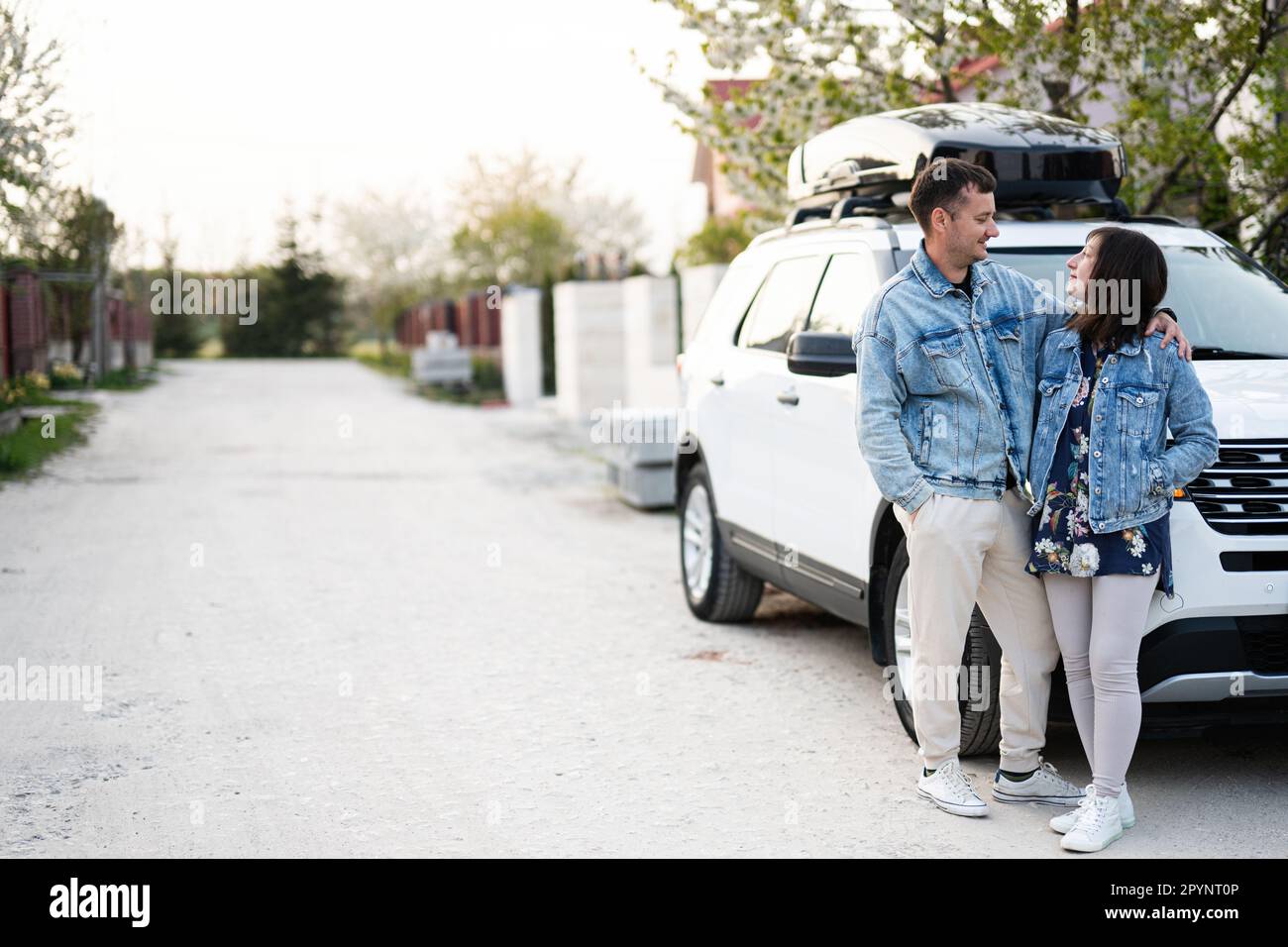 Stylish couple in jeans jacket standing near white american suv car ...