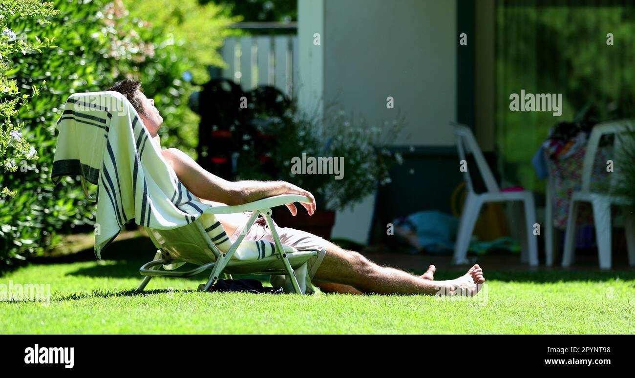Candid man relaxing outside sunbathing in backyard yard Stock Photo Alamy