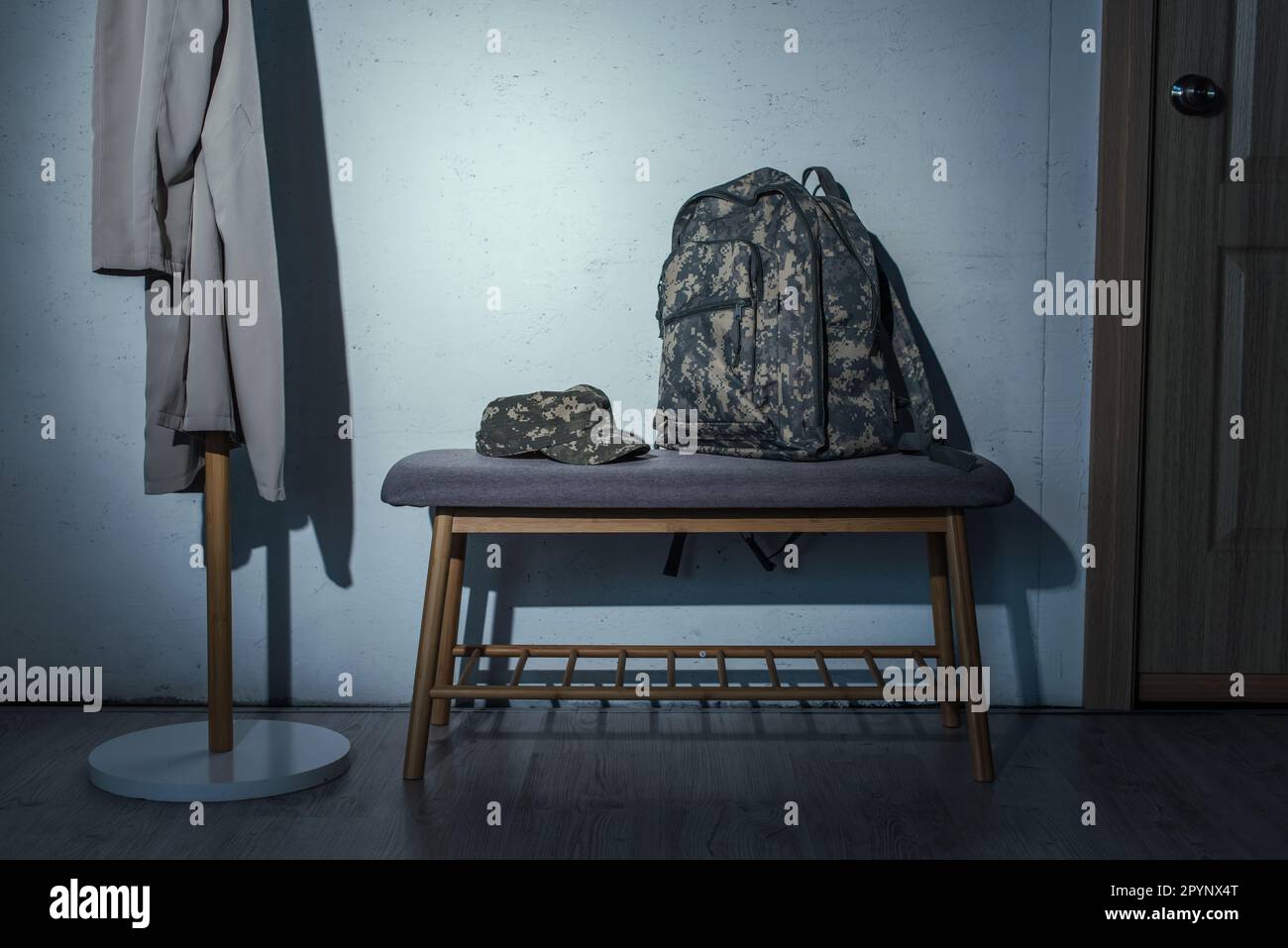 Military backpack and cap on bench in hallway at home at night,stock image Stock Photo