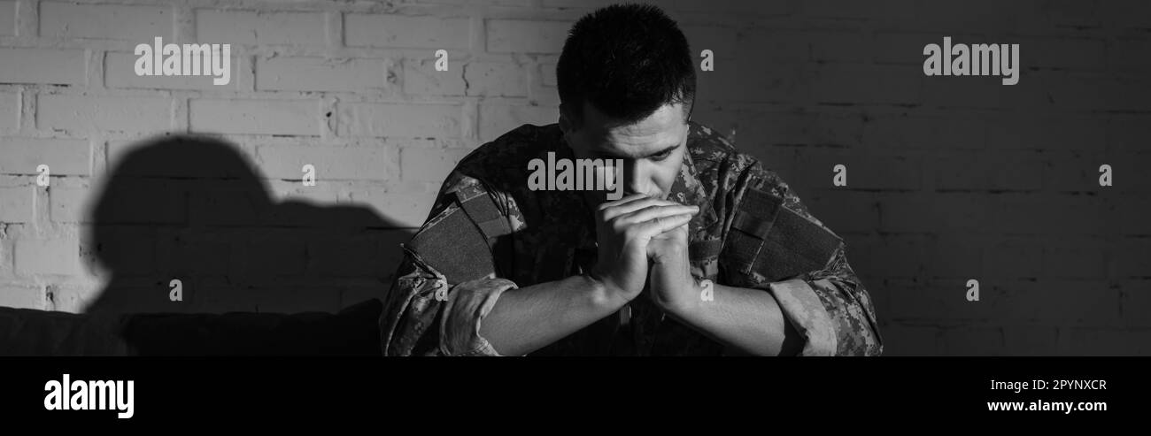 Black and white photo of frustrated military veteran with ptsd problem sitting at home, banner,stock image Stock Photo