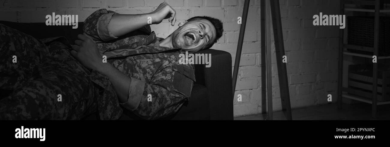 black and white photo of anxious serviceman screaming while suffering from post traumatic stress disorder, banner,stock image Stock Photo