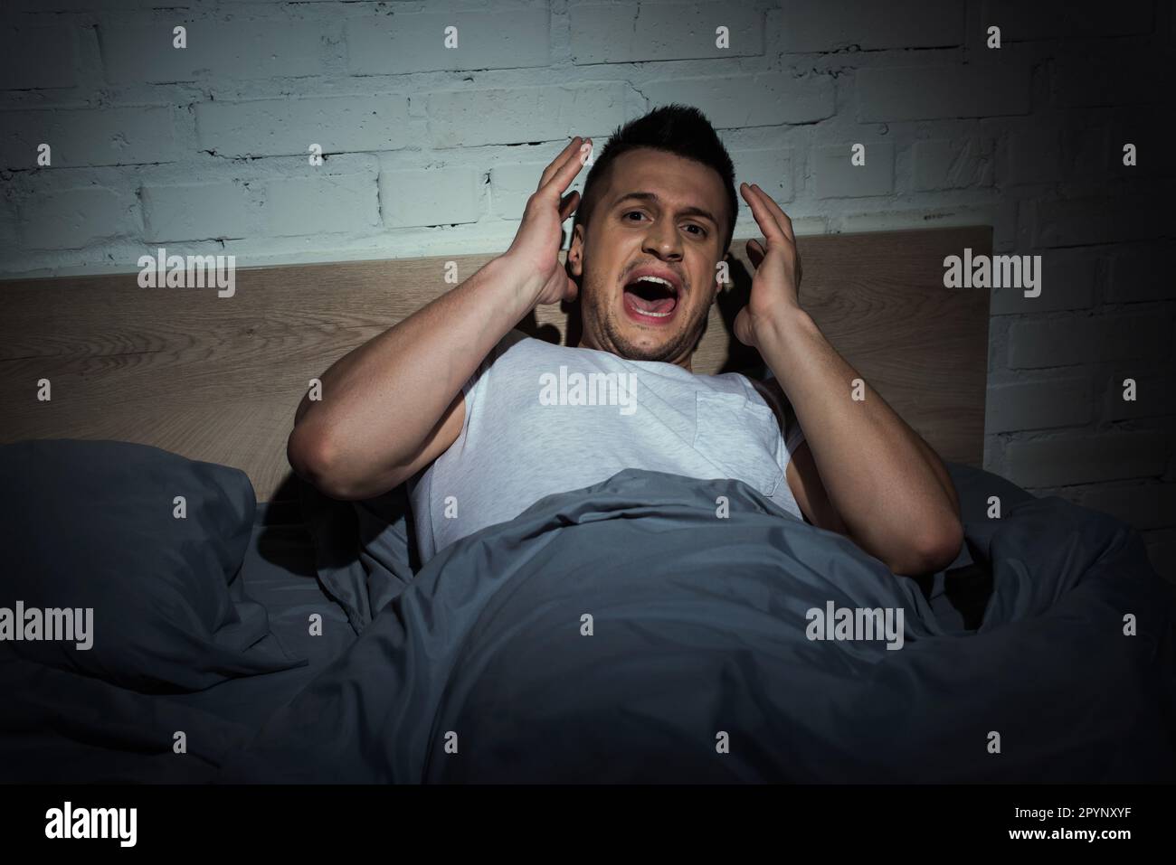 stressed man with panic attacks screaming while having nightmare at night,stock image Stock