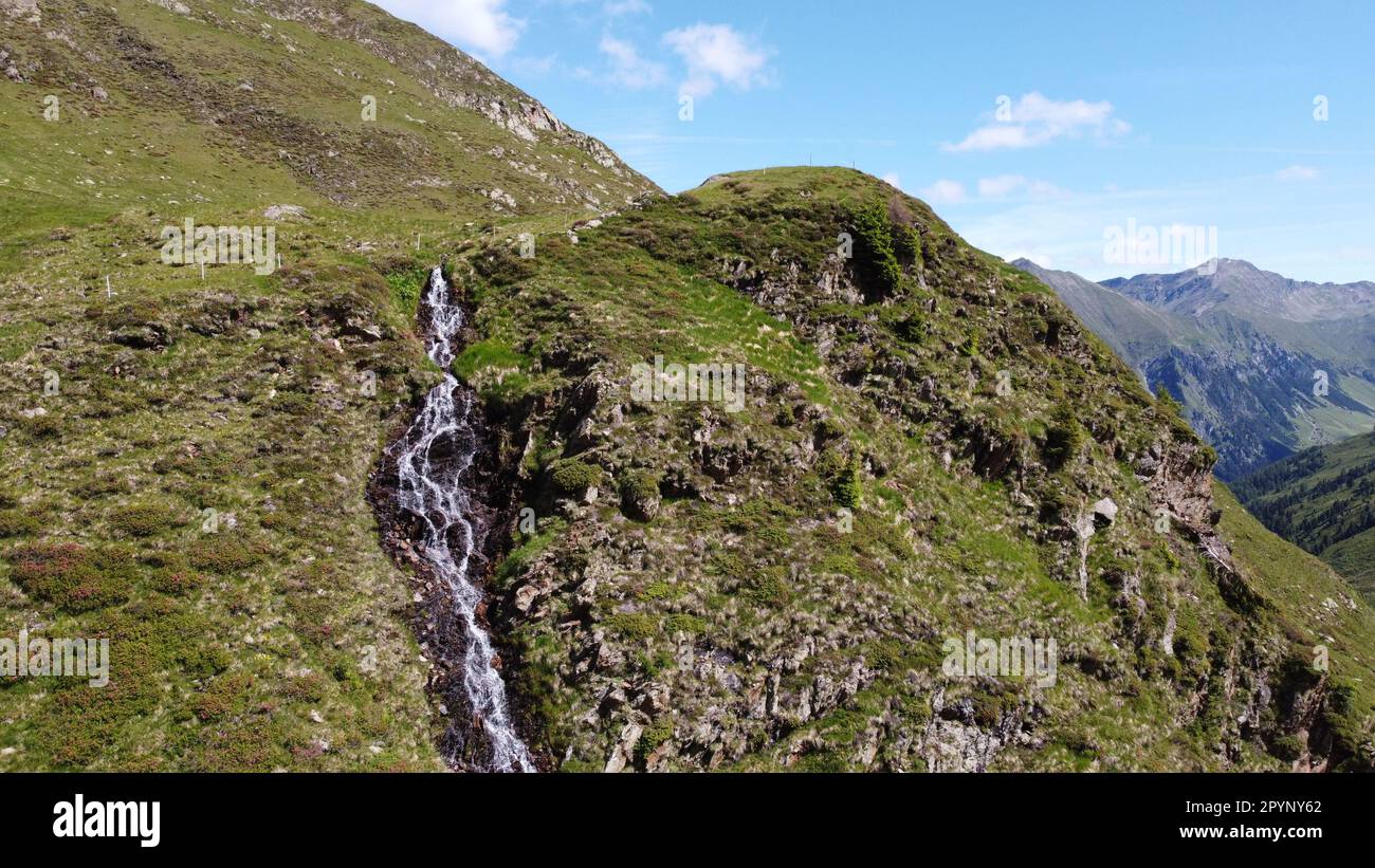 Wasserfall umgeben von grünen Wiesen, mitten in den Bergen Stock Photo