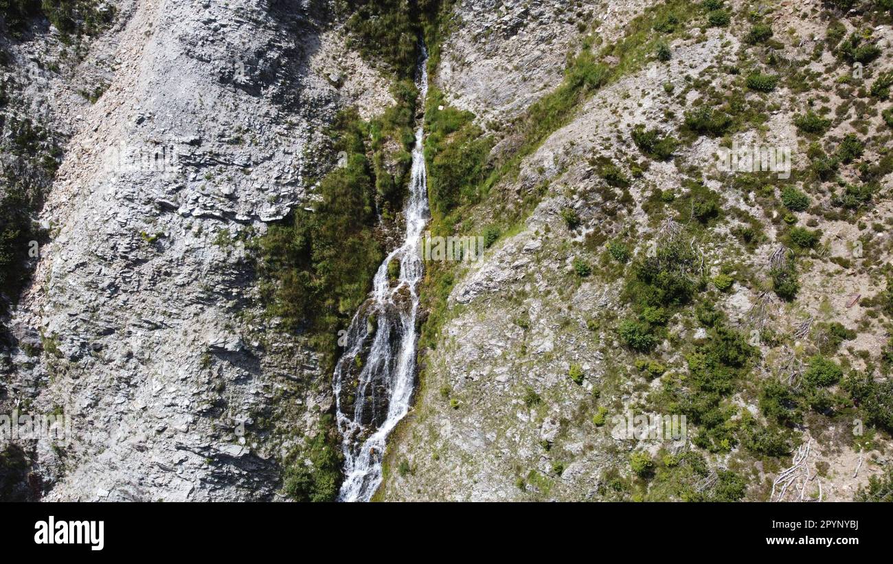 Wasserquelle, welche mitten aus dem Berg austritt und über einen spektakulären Wasserfall ins Tal fließt Stock Photo