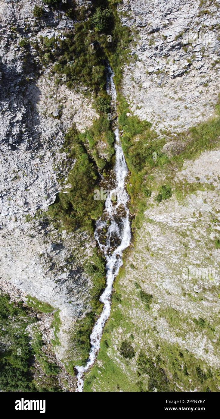 Wasserquelle, welche mitten aus dem Berg austritt und über einen spektakulären Wasserfall ins Tal fließt Stock Photo