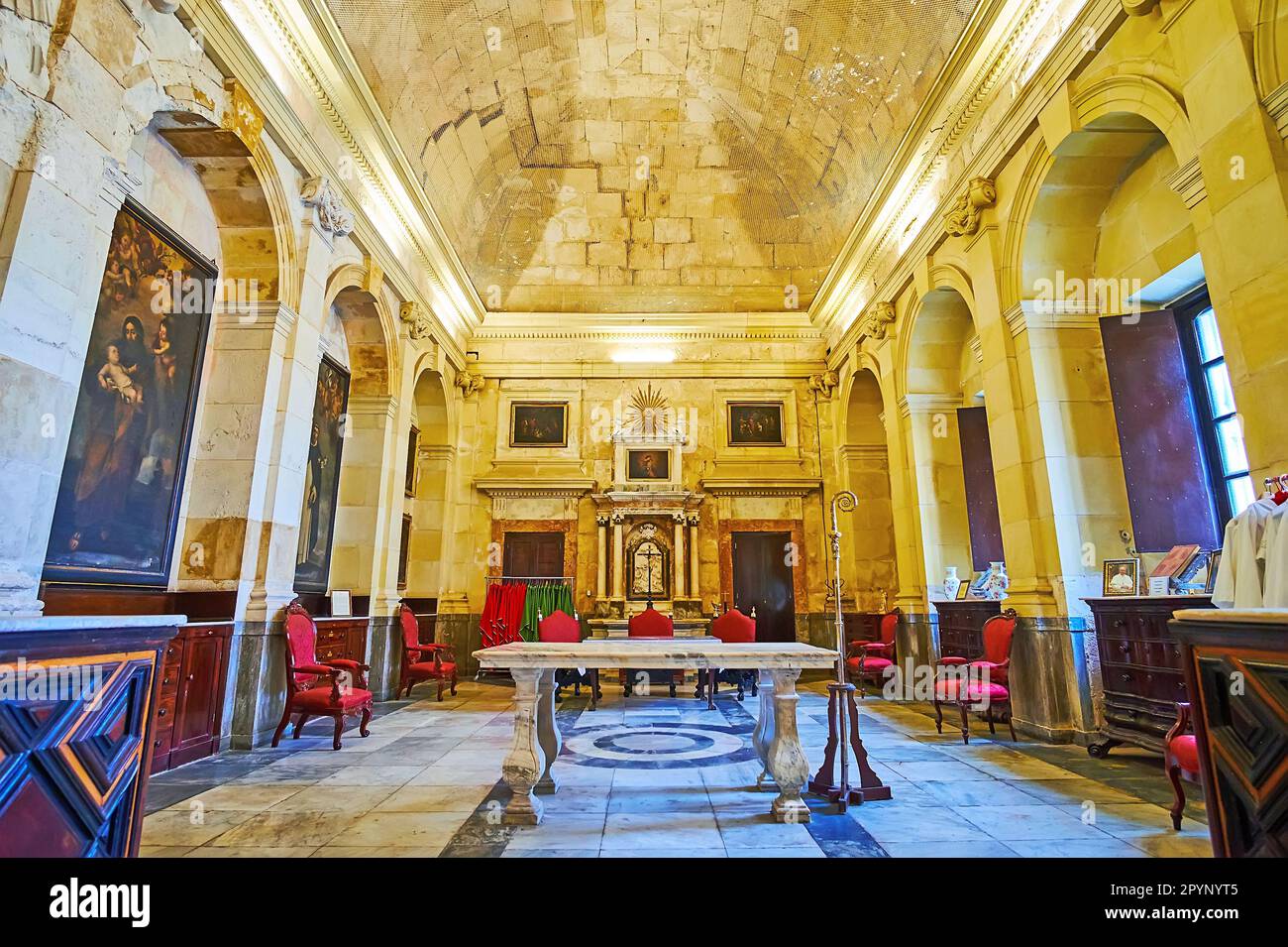 CADIZ, SPAIN - SEPT 21, 2019: Interior of Sacristy of Santa Cruz Sobre el Mar Cathedral with stone table, carved wooden chair, historic paintings, on Stock Photo