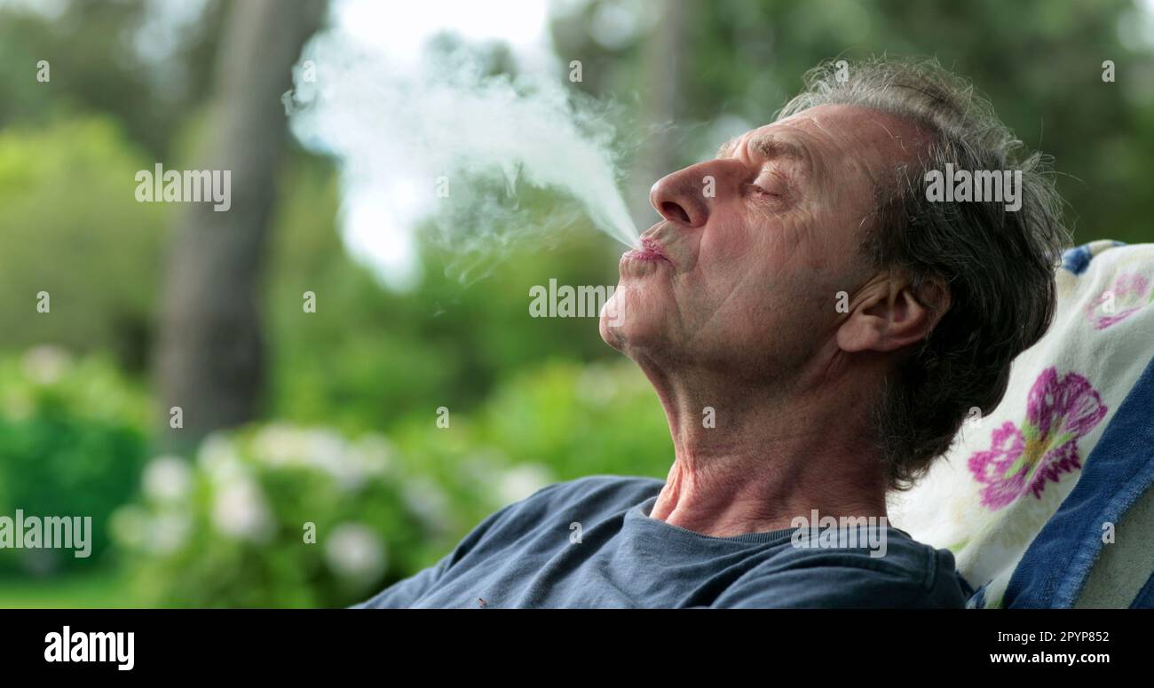 Elder man smoking cigar inhaling smoke outdoors Stock Photo Alamy
