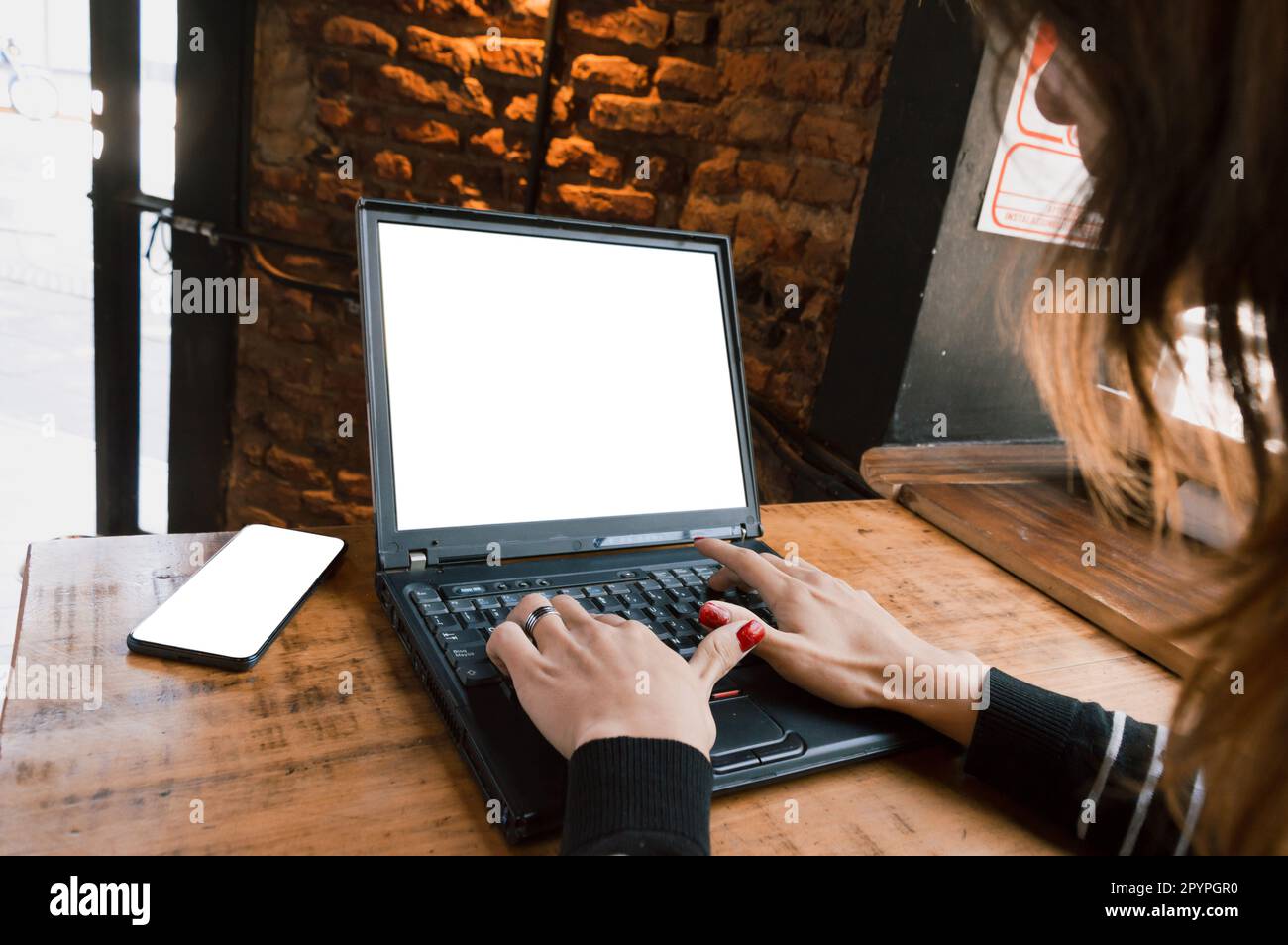 Young transgender Argentinian freelance Latina woman, typing on the laptop surfing the internet working in her online business. Stock Photo