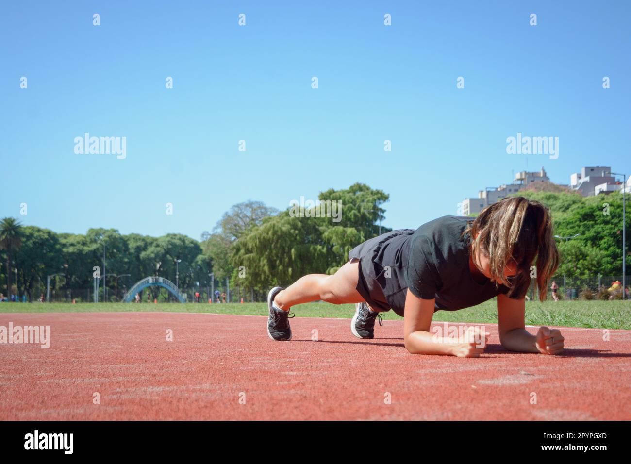 young latin woman in black sportswear, training doing plank muscle crunch on running track, sport concept, copy space. Stock Photo
