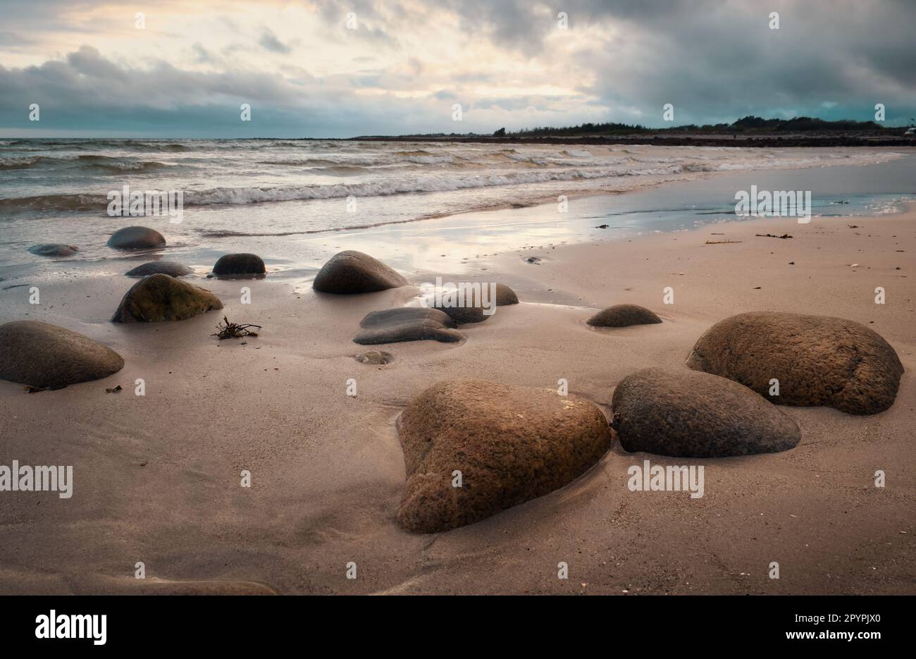 Dramatic cloudy coastal landscape scenery with pebbles on sandy
