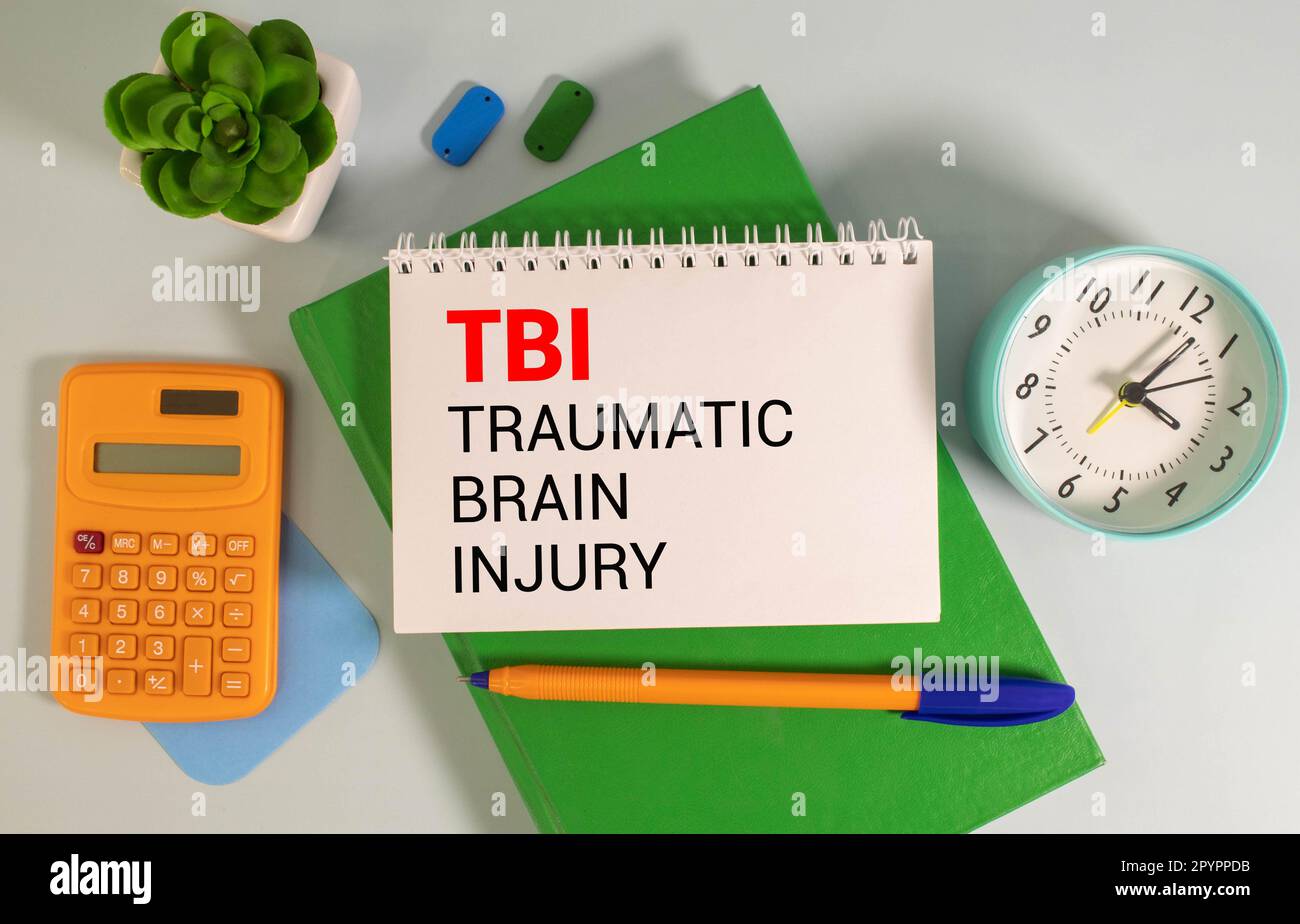 TBI traumatic brain injury symbol. Concept words TBI traumatic brain injury on white note on a beautiful wooden table wooden background. Pen. Medical Stock Photo