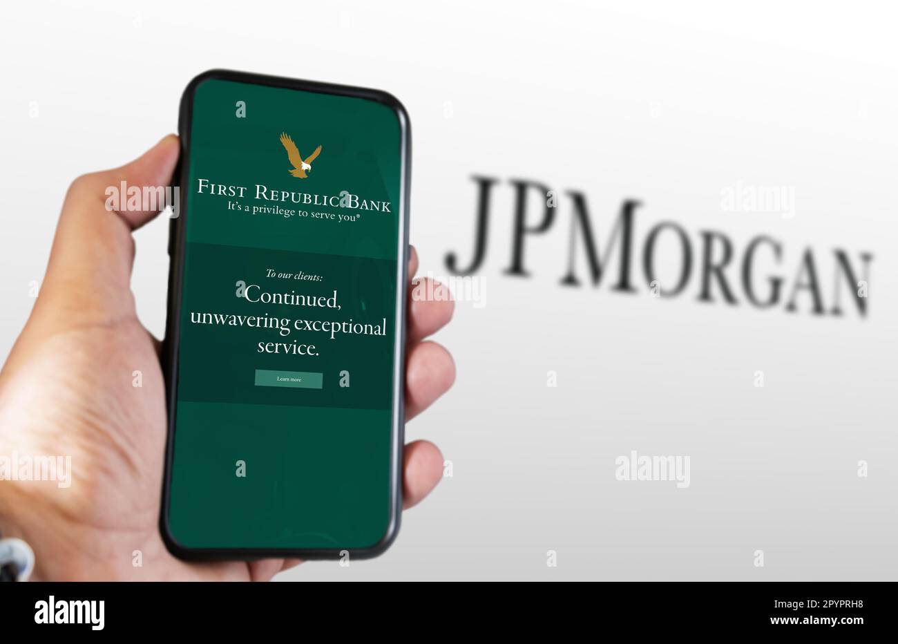 San Francisco, US, March 2023: Hand holding a phone with the First Republic Bank logo on the screen and JPMorgan logo blurred in the background. FRB w Stock Photo