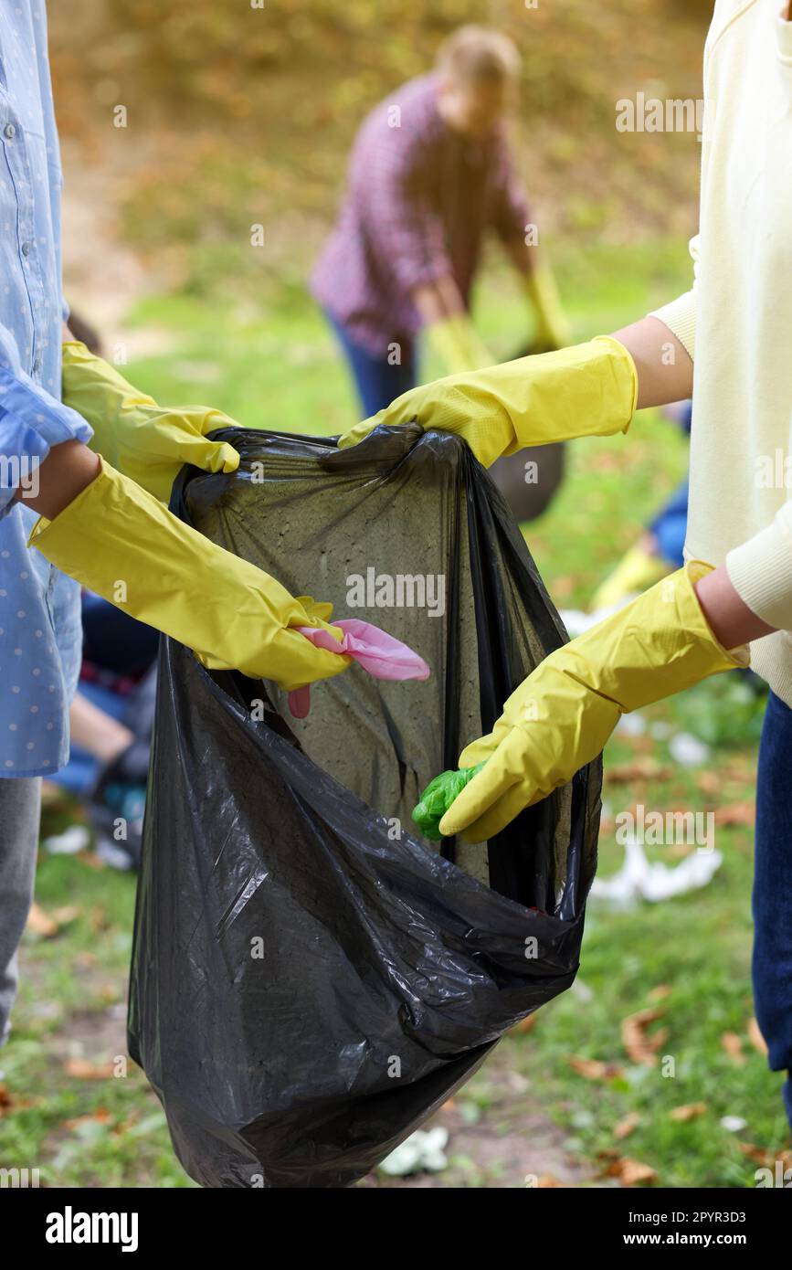 Women with plastic bag collecting garbage in park, closeup Stock Photo