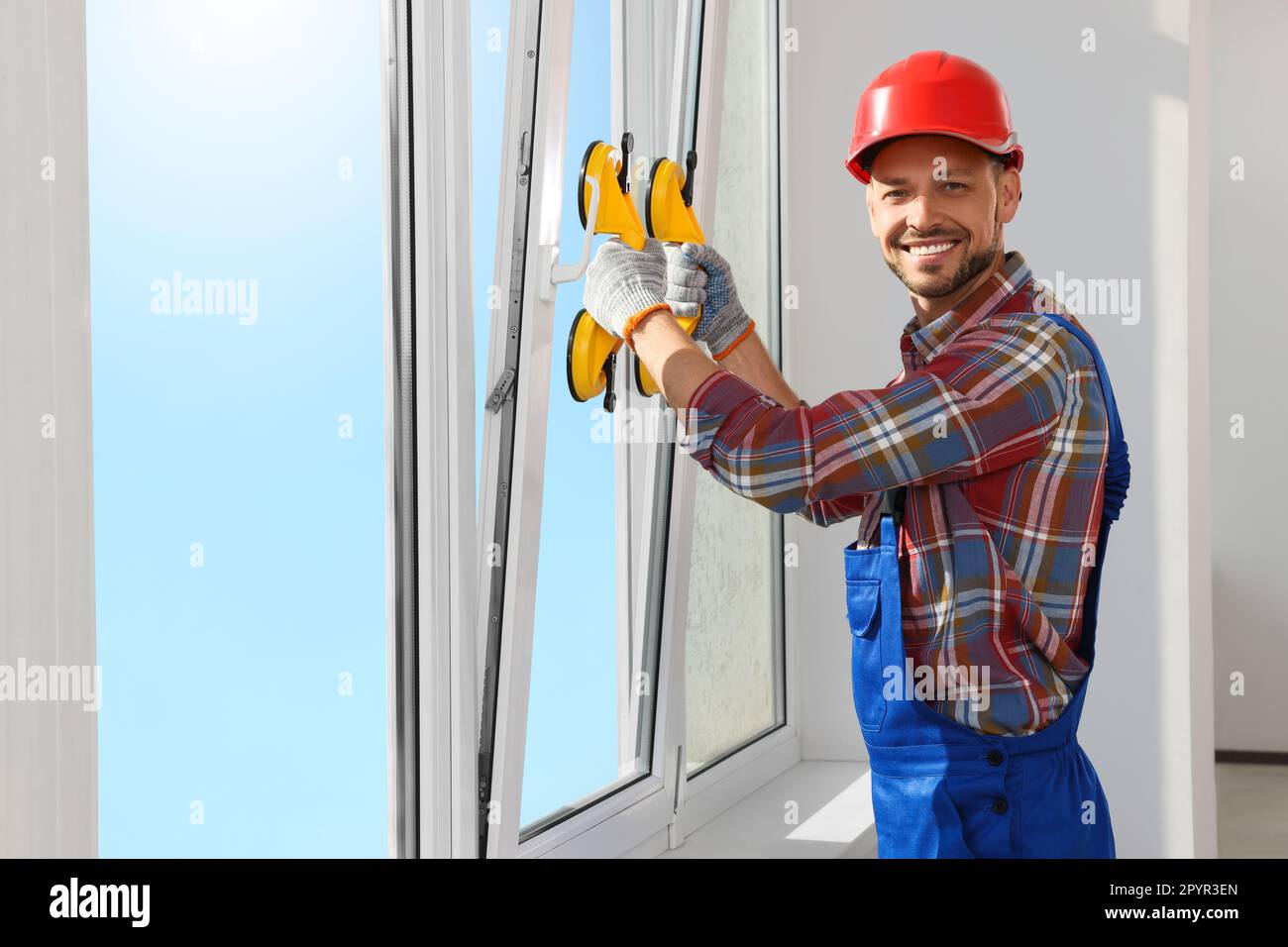 Worker using suction lifters during plastic window installation indoors Stock Photo