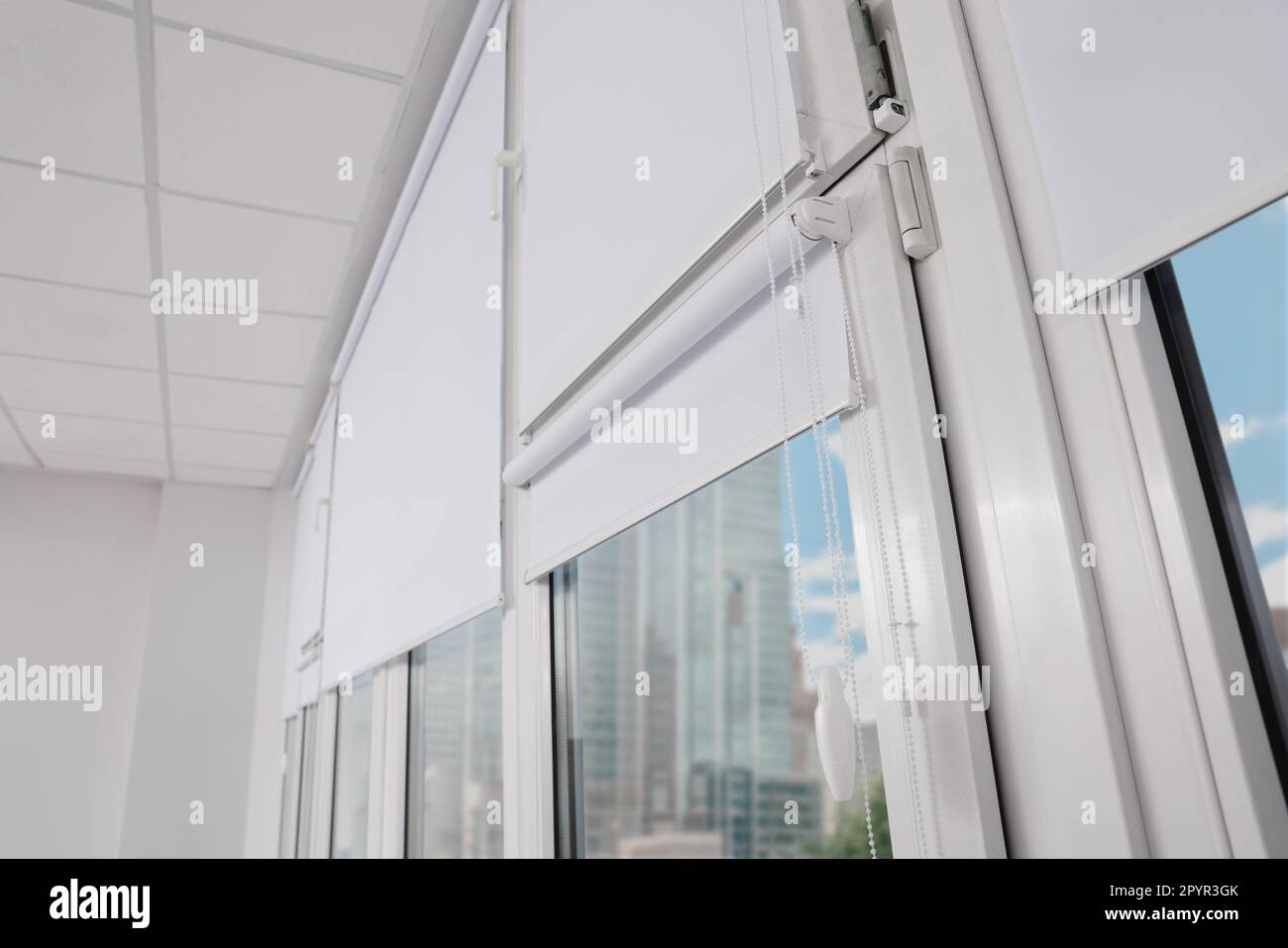 Plastic windows with white roller blinds indoors Stock Photo