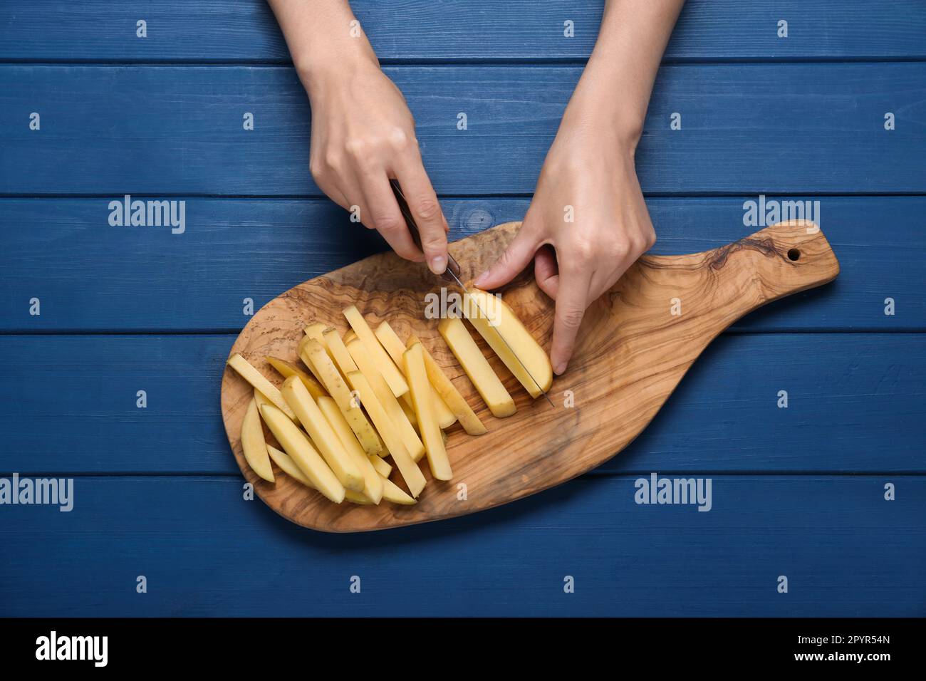 https://c8.alamy.com/comp/2PYR54N/woman-cutting-potato-at-blue-wooden-table-top-view-cooking-delicious-french-fries-2PYR54N.jpg