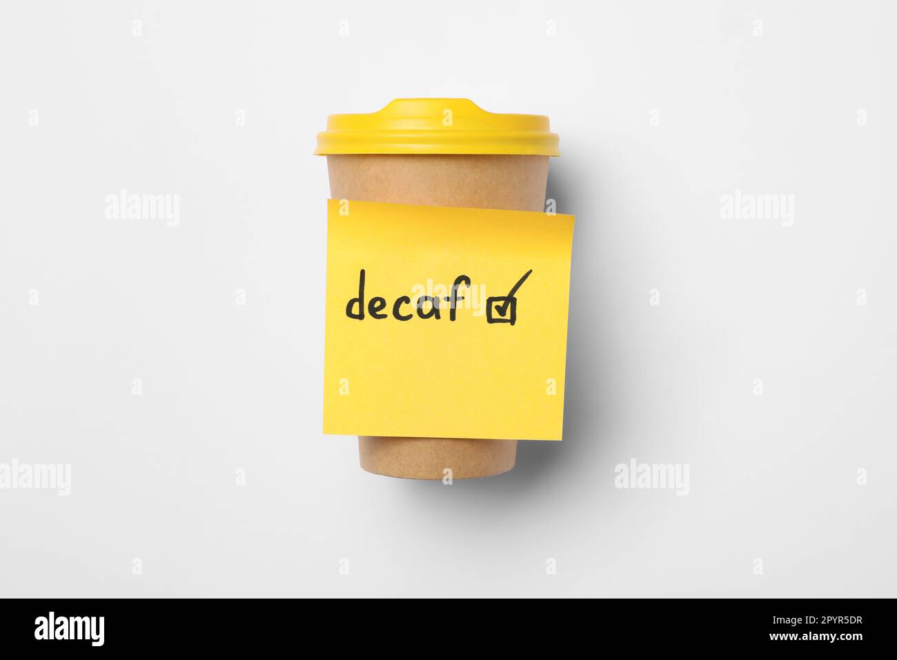 Note with word Decaf and checkbox attached to takeaway coffee cup on white background, top view Stock Photo