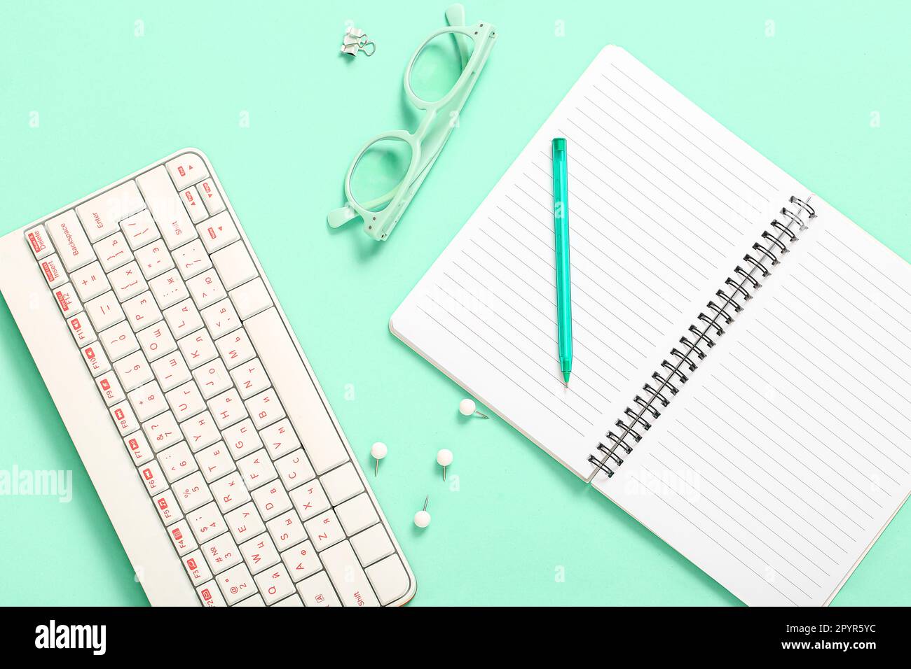 Composition with glasses, keyboard and notebook on turquoise background ...