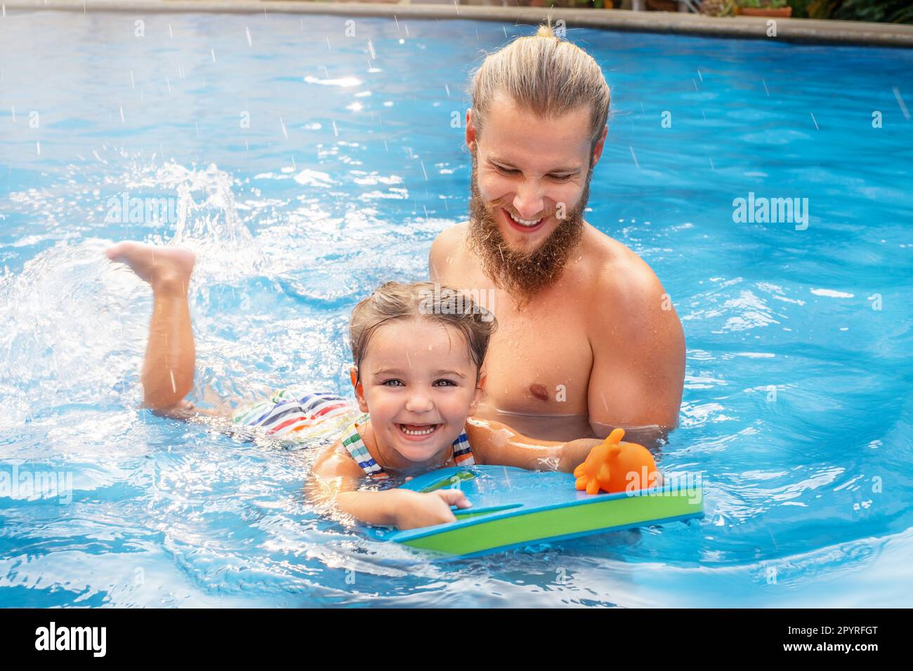 child learns to swim in the pool with dad Stock Photo