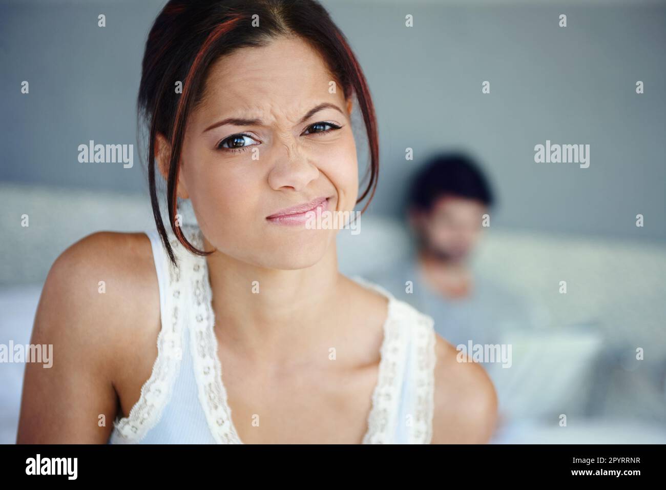 Im not impressed. Portrait of a woman scrunching up her face sitting in her bedroom with her
