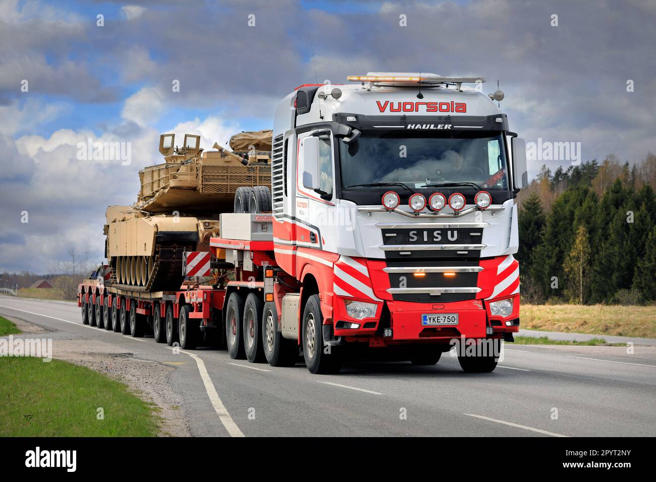 Sisu Polar Hauler truck hauls American M1 Abrams military tank on low loader trailer. Convoy of 3 oversize transports. Salo, Finland. April 28, 2023. Stock Photo