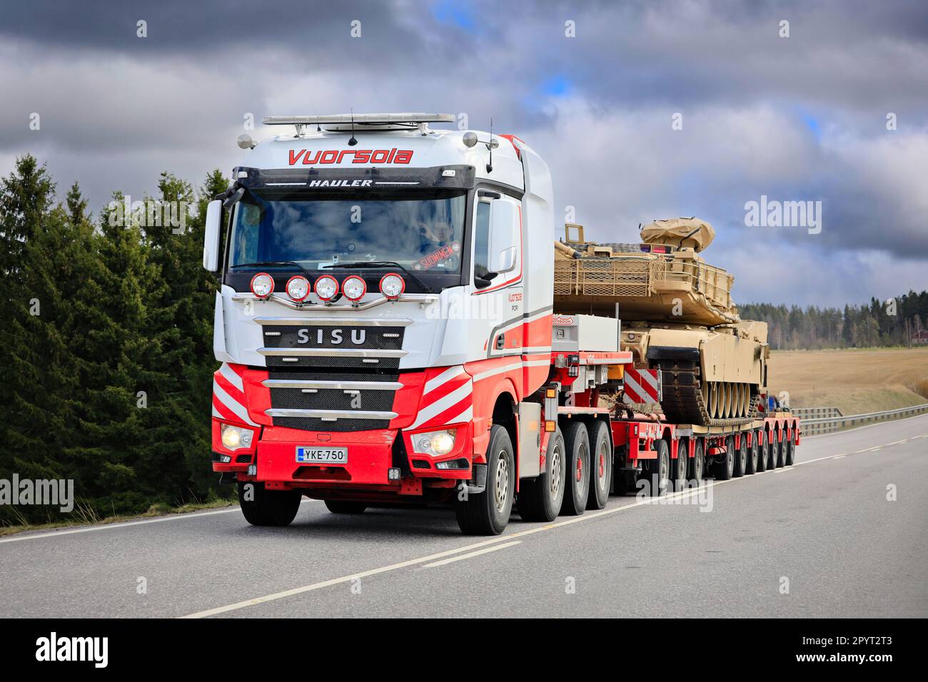 Sisu Polar Hauler truck hauls American M1 Abrams military tank on low loader trailer. Convoy of 3 oversize transports. Lieto, Finland. April 28, 2023. Stock Photo
