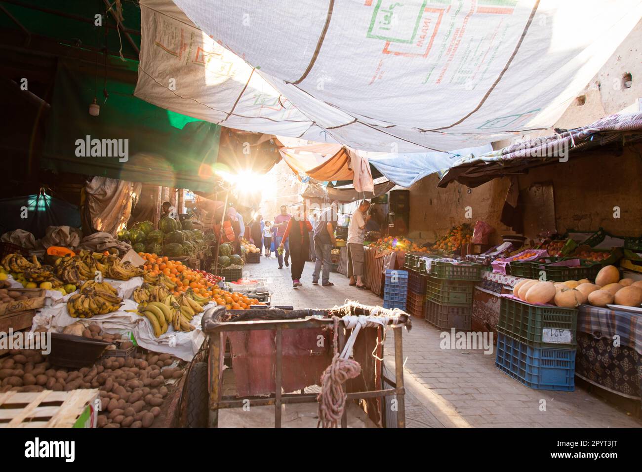 Fez, Morocco 2022: historical and traditional narrow streets of Fes el-Bali, the old Medina,  with shops of vegetables in the souk (suq) and people Stock Photo