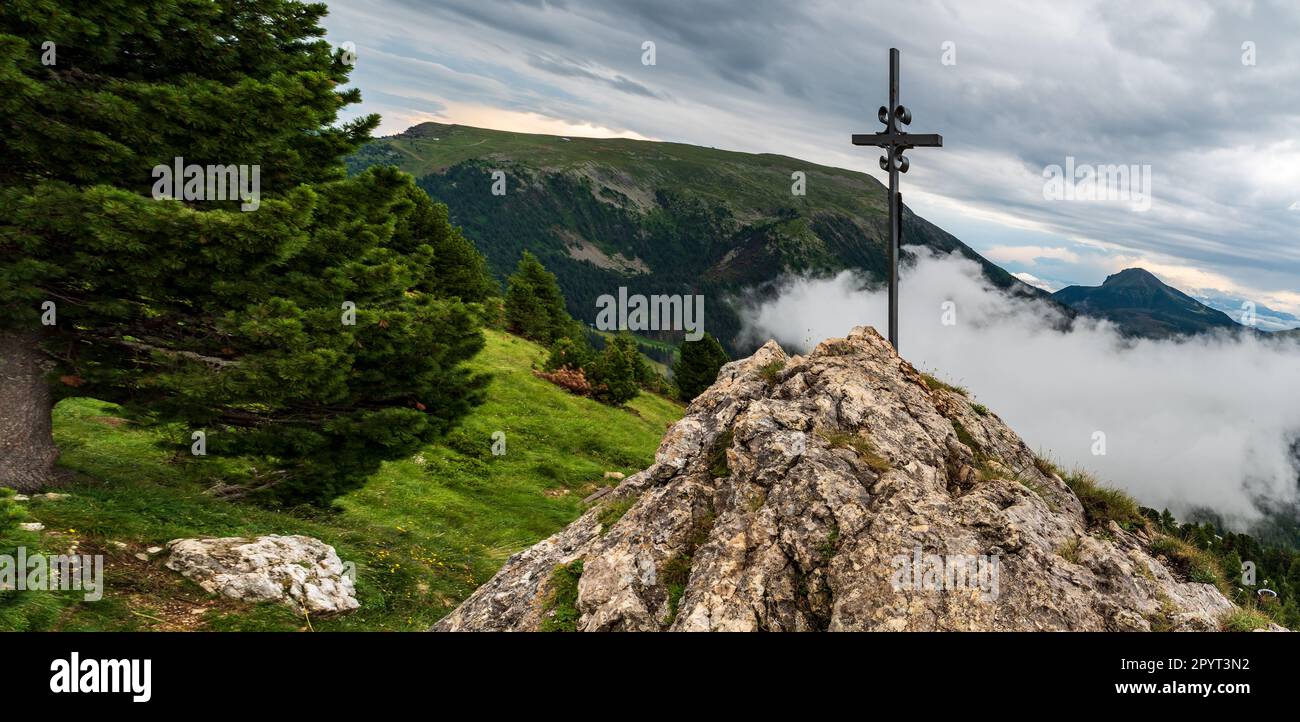 rock with cross and Pala di Santa hill from hiking trail above Oberholtz Hutte in the Dolomites Stock Photo