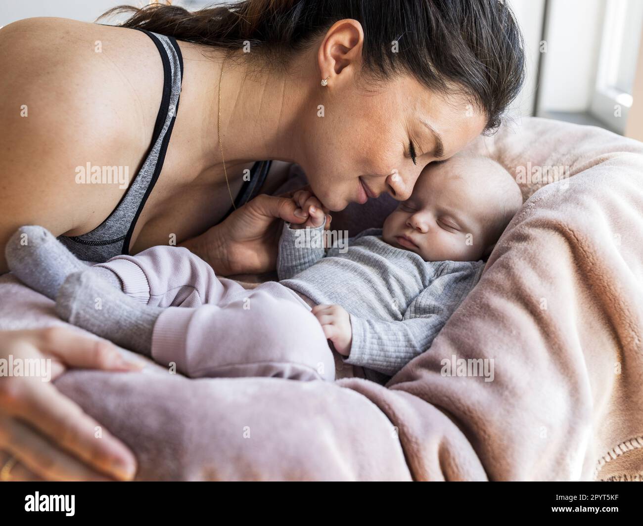 Mom cuddling with newborn baby who sleeping and holding mom's finger ...