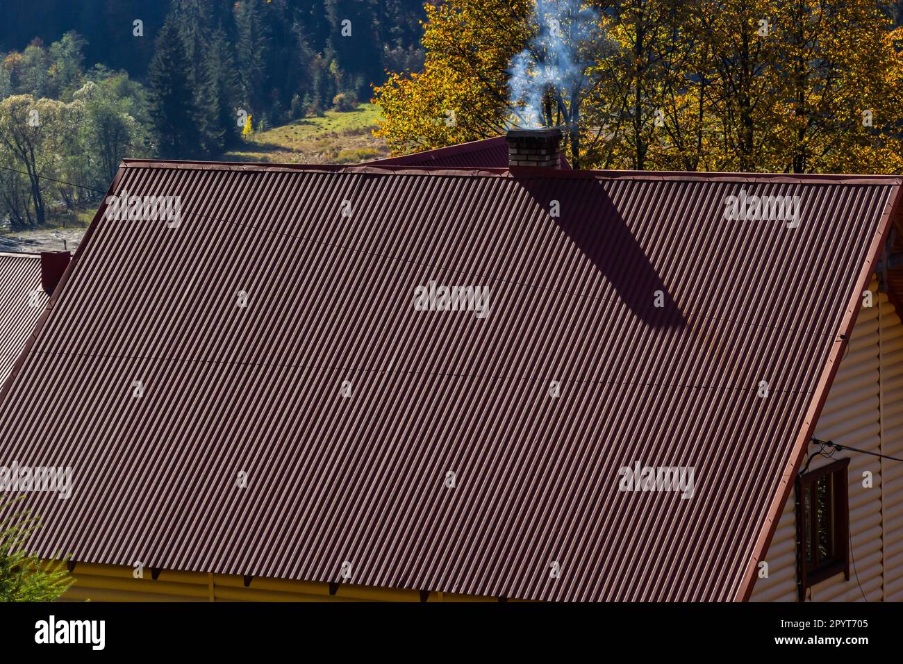 House with new brown metal tile roof and rain gutter. Metallic