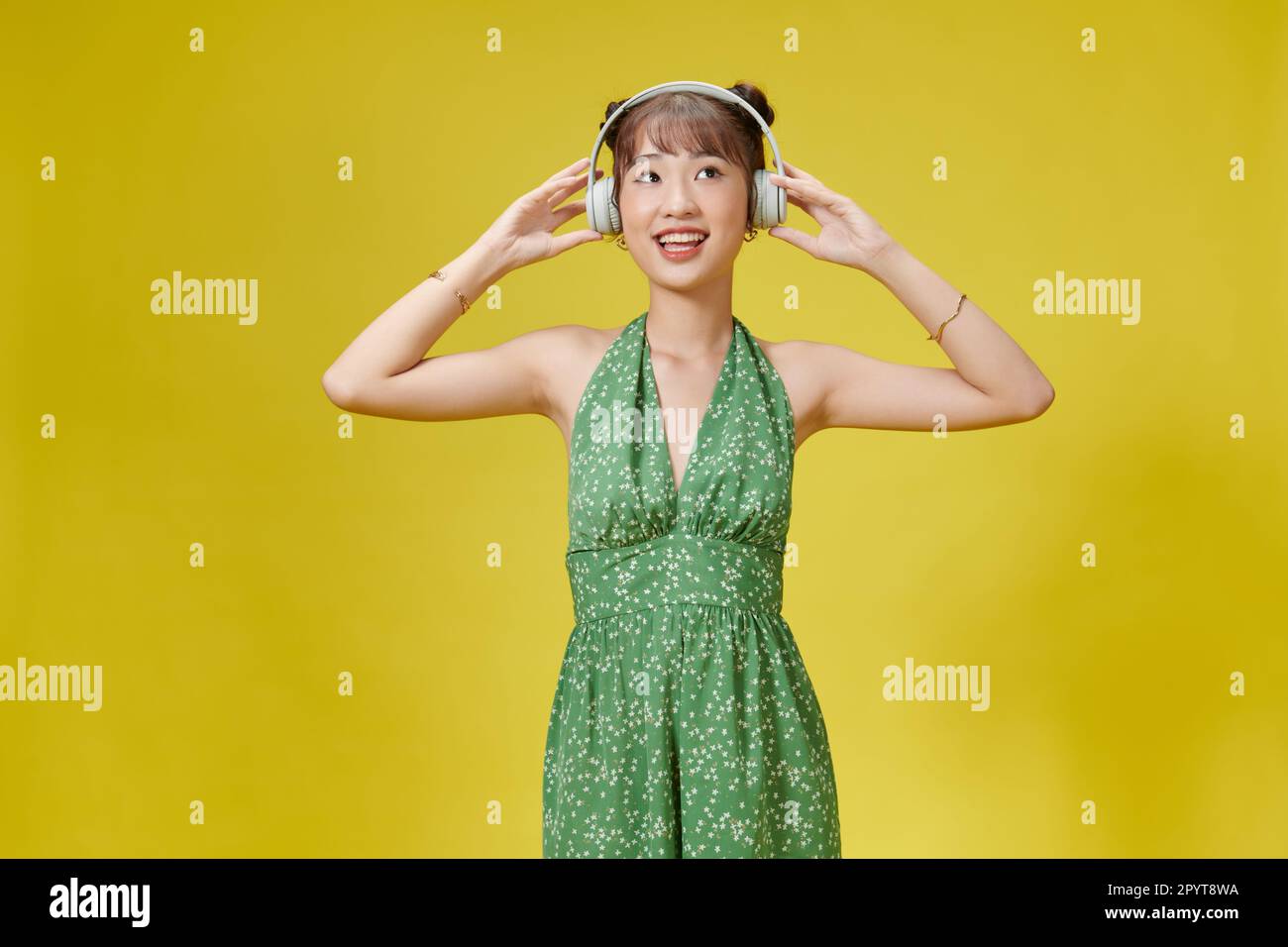 Happy Asian woman wearing headphones listening to music from smartphone ...