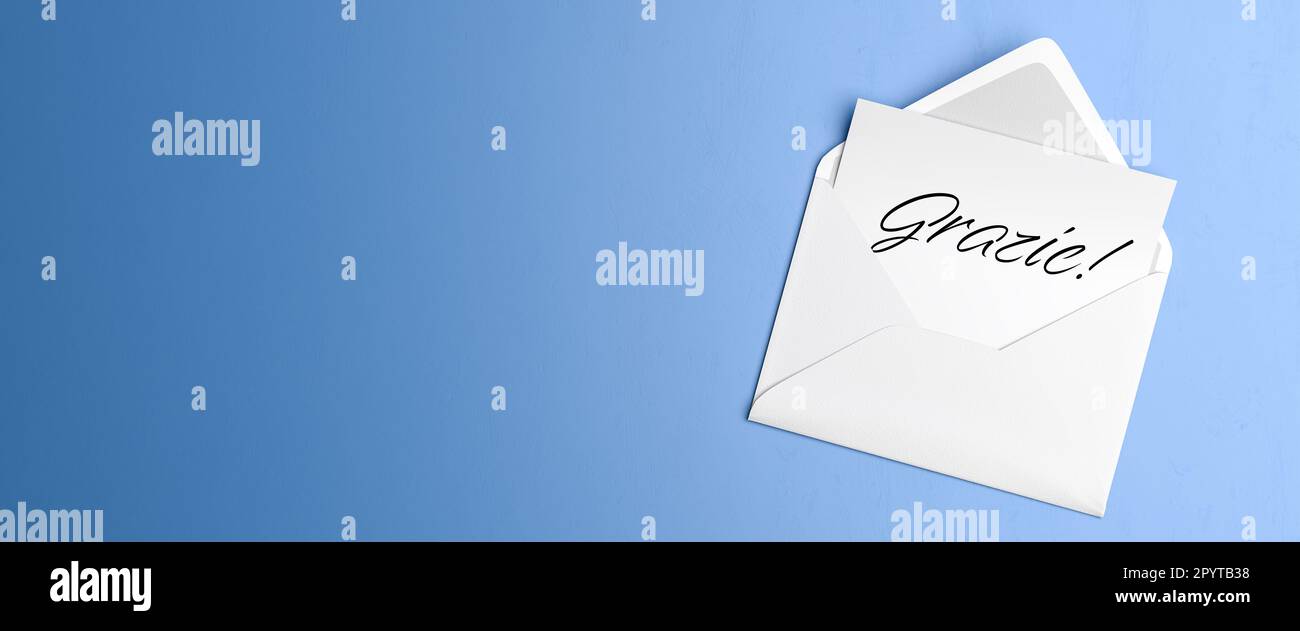 Letter with the Italian text 'Grazie' ('Thanks') in an envelope on blue table background. Stock Photo