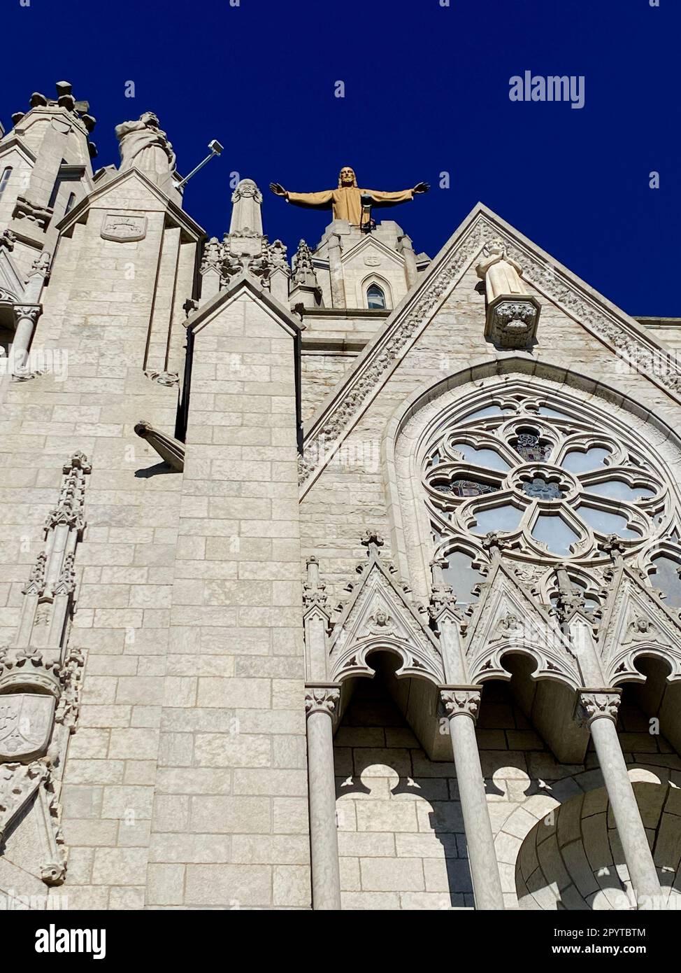 A statue of Jesus standing atop a grand edifice made of stone, illuminated by the sun's rays Stock Photo