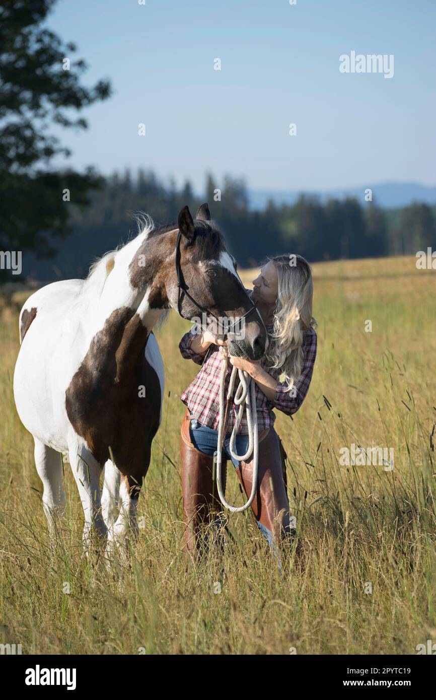 Mid adult woman standing with her horse on meadow, Bavaria, Germany Stock Photo