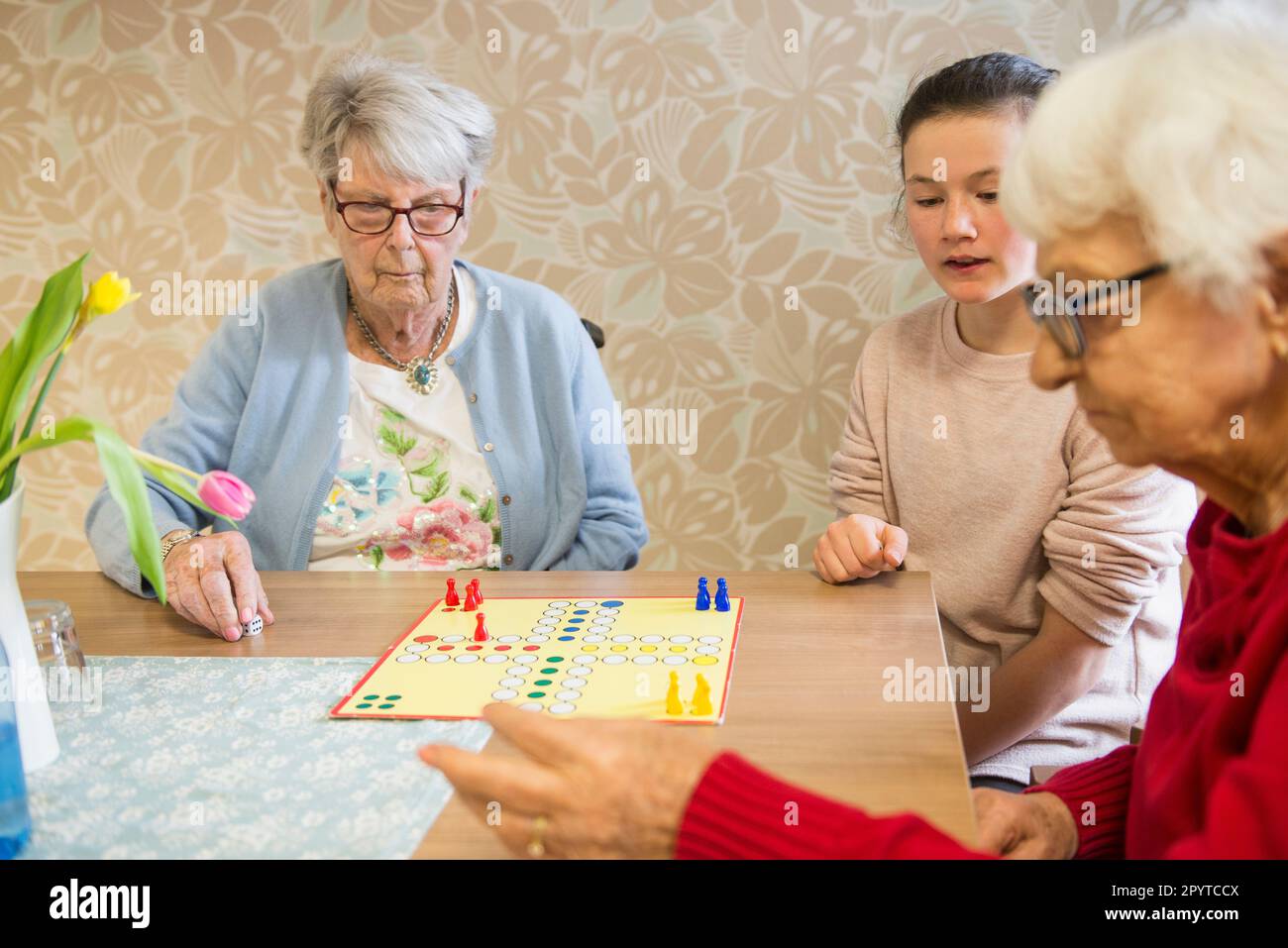 Girl playing board game with senior women in rest home Stock Photo