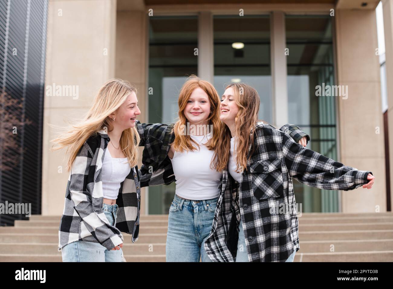 Three laughing teen girls hugging outdoors on steps Stock Photo - Alamy