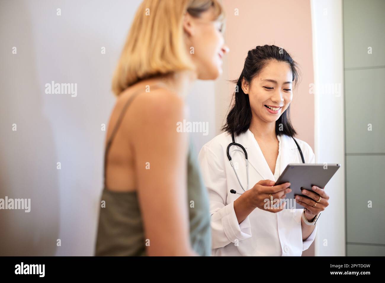 Smiling doctor using tablet PC while sitting with female patient Stock Photo
