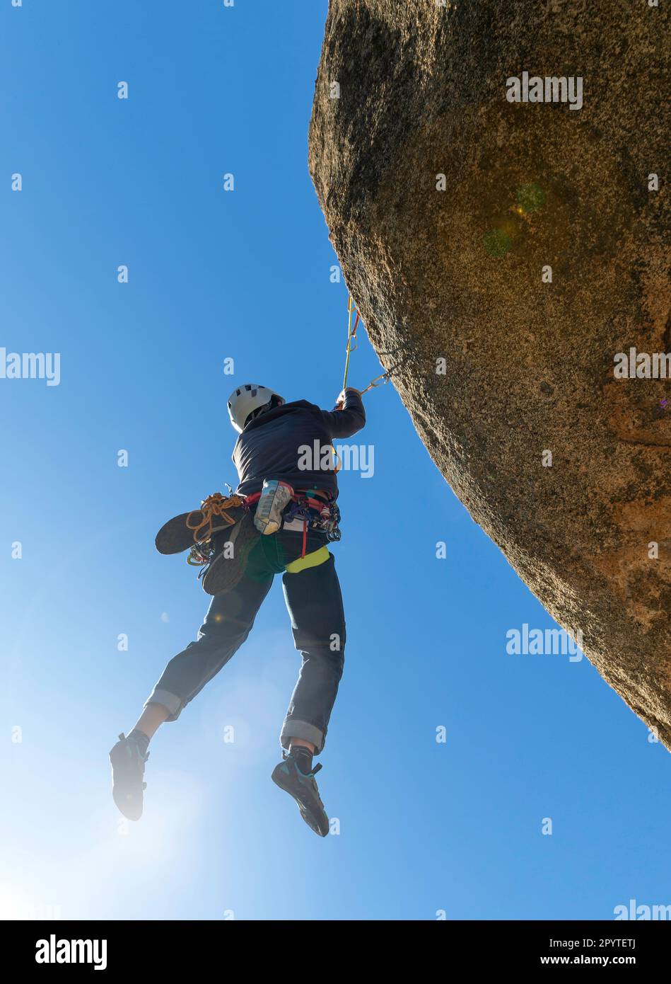 young adult hanging from a granite overhang. Rock climbing. Extreme