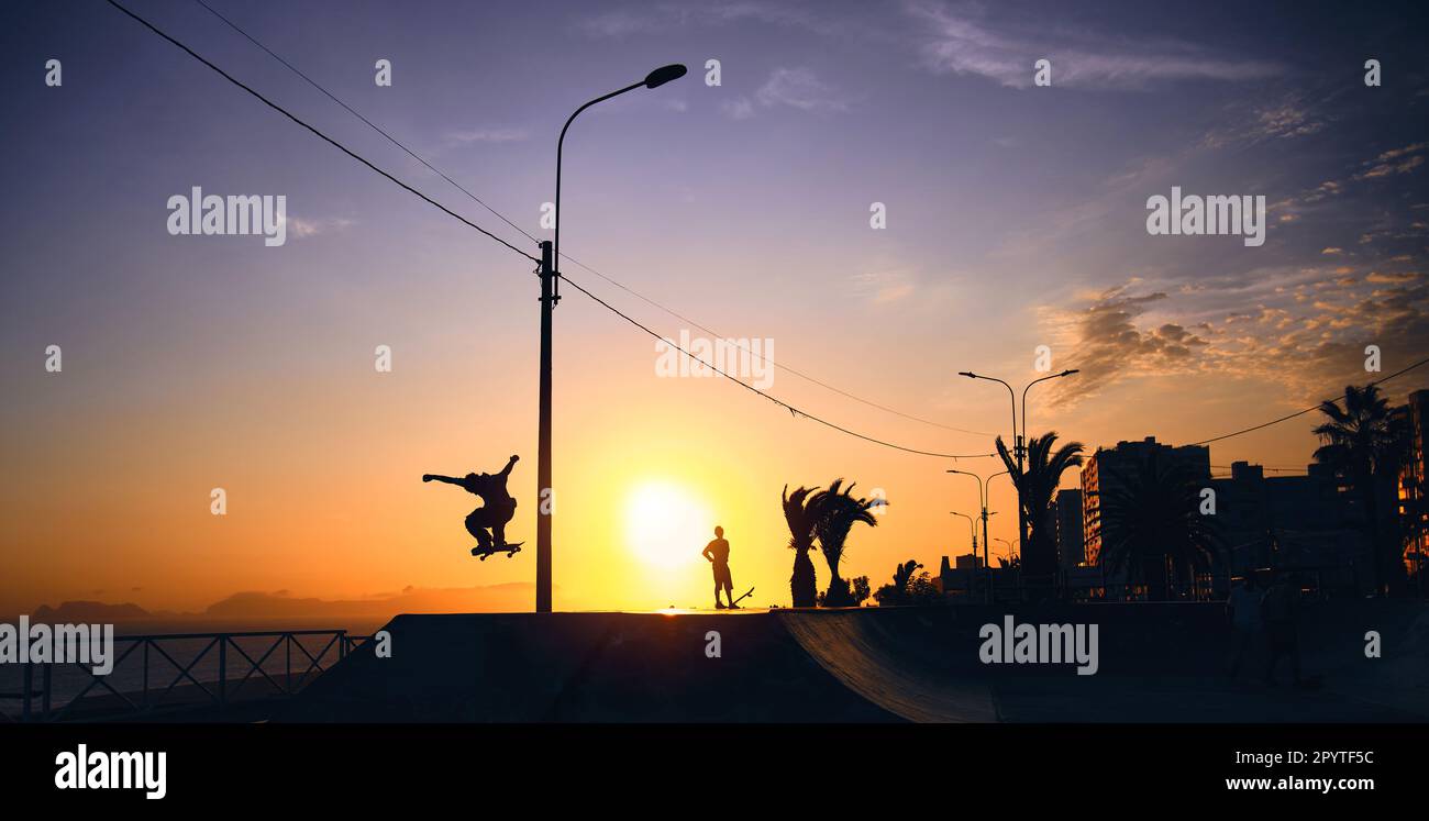 Silhouette of young jumping skateboarder riding, summer sunset. Stock Photo