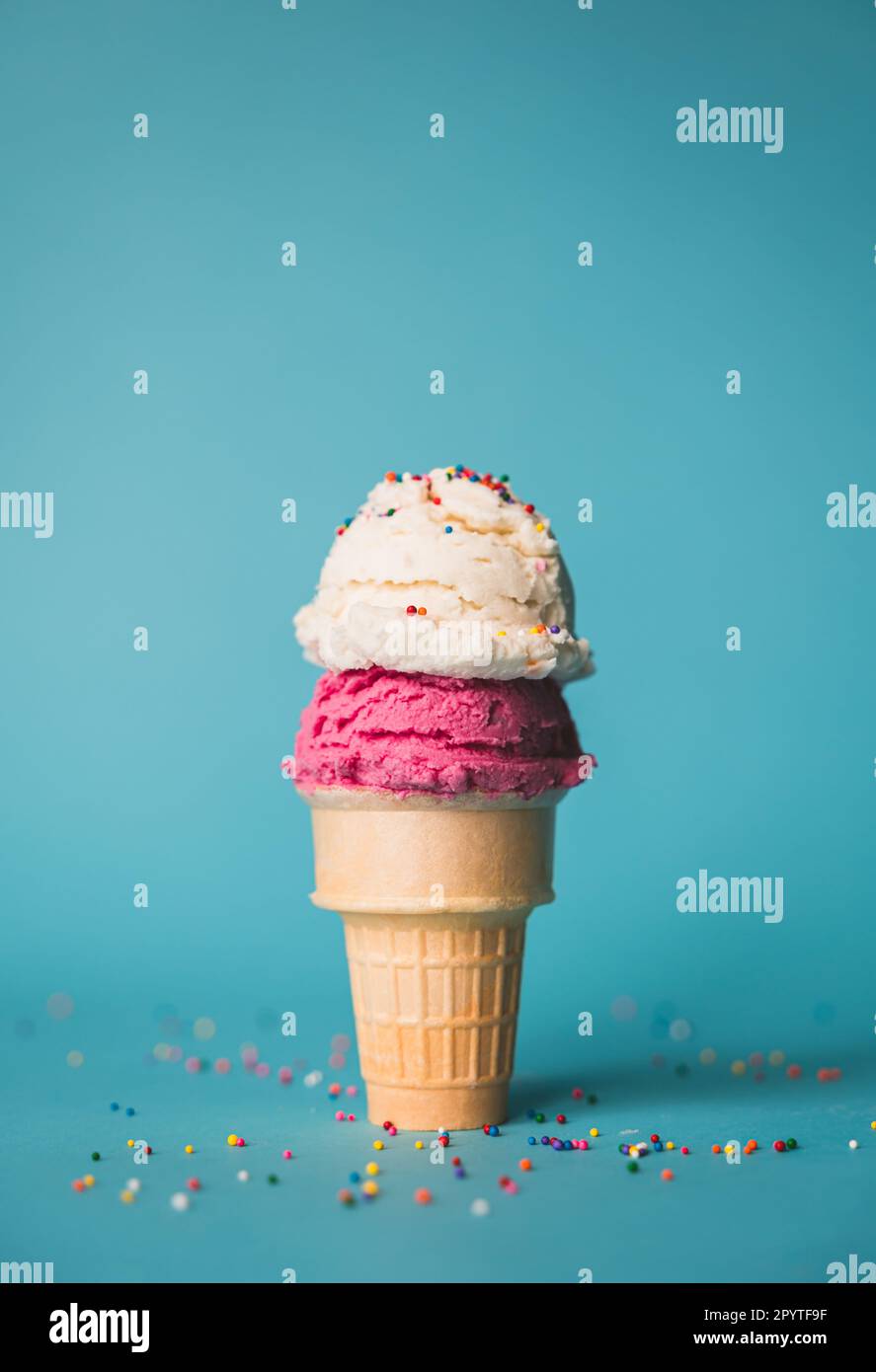 Ice cream cone with two scoops and sprinkles on blue background. Stock Photo