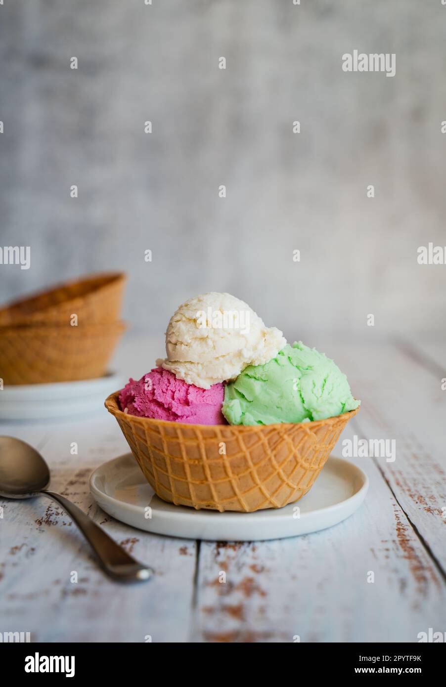 Three scoops of ice cream in a waffle bowl on weathered wood table Stock Photo Alamy