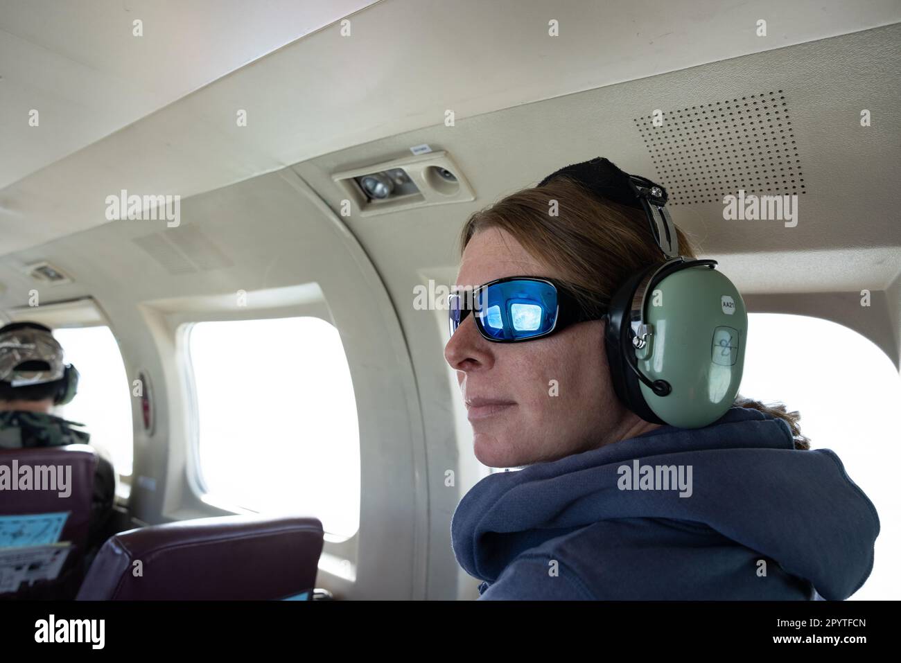 Woman passenger on small airplane with headset over Alaska Stock Photo