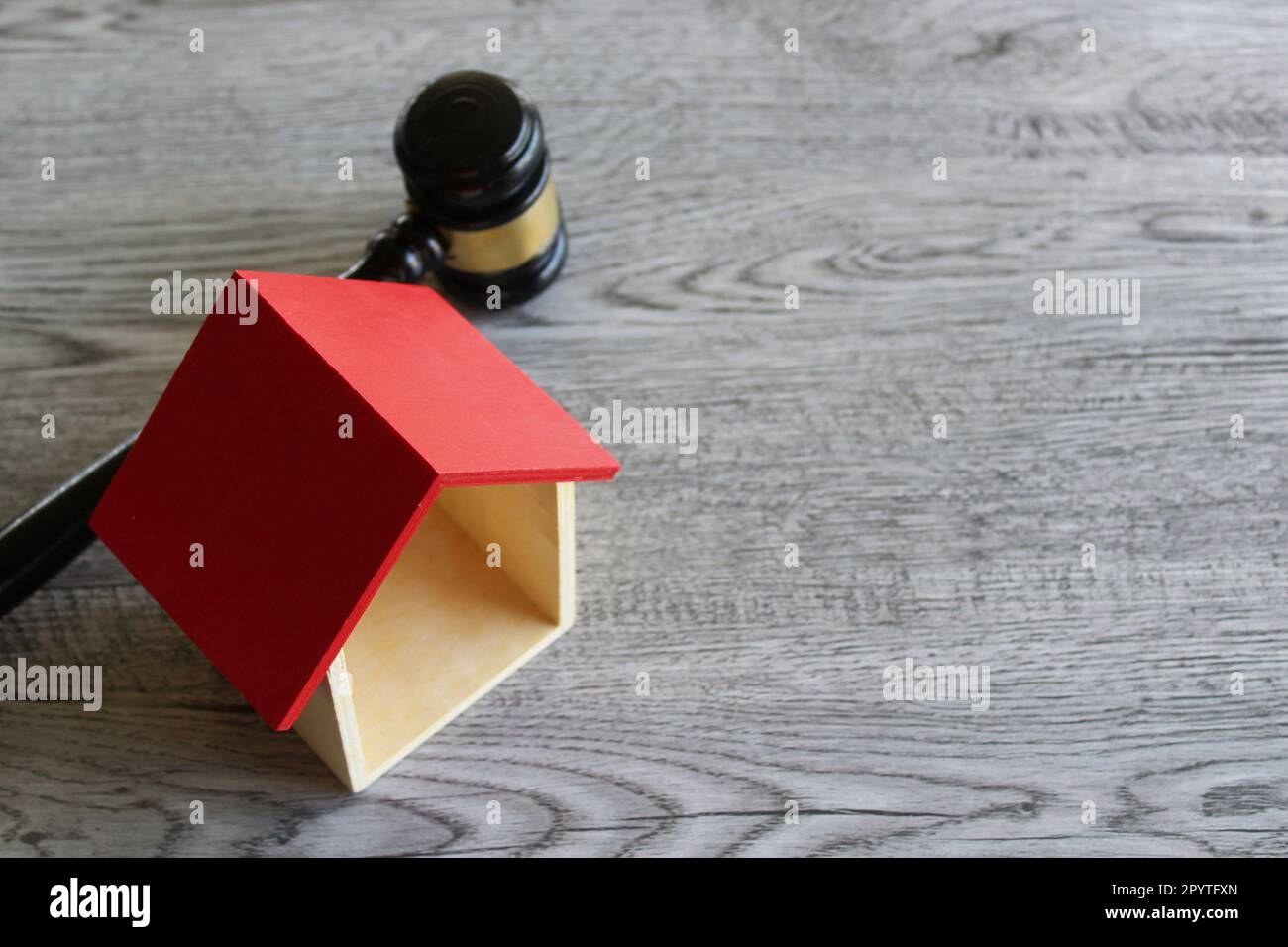 Toy house and judge gavel on wooden table with copy space. Real estate law and house auction concept Stock Photo